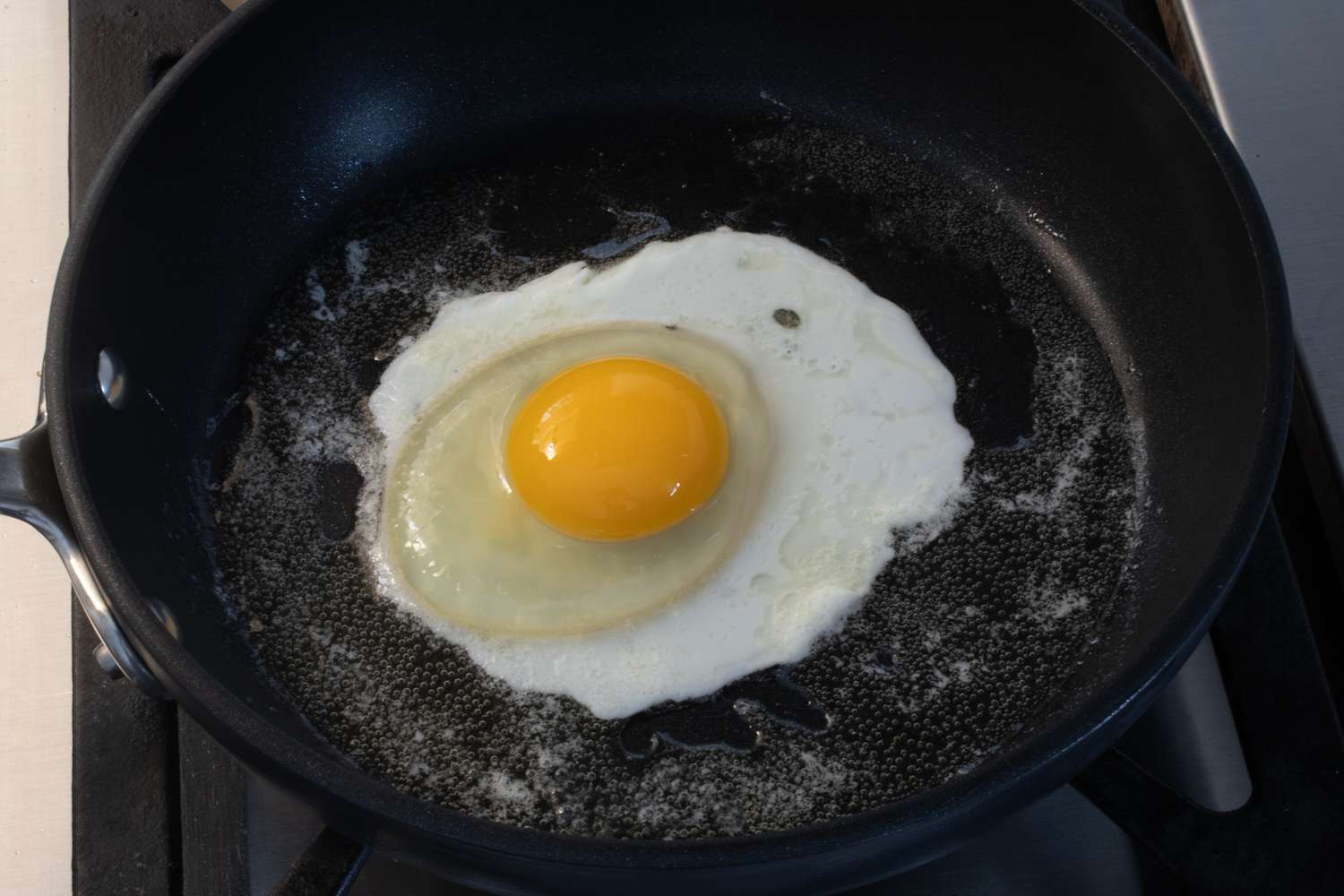 Egg with yolk intact cooking in the skillet