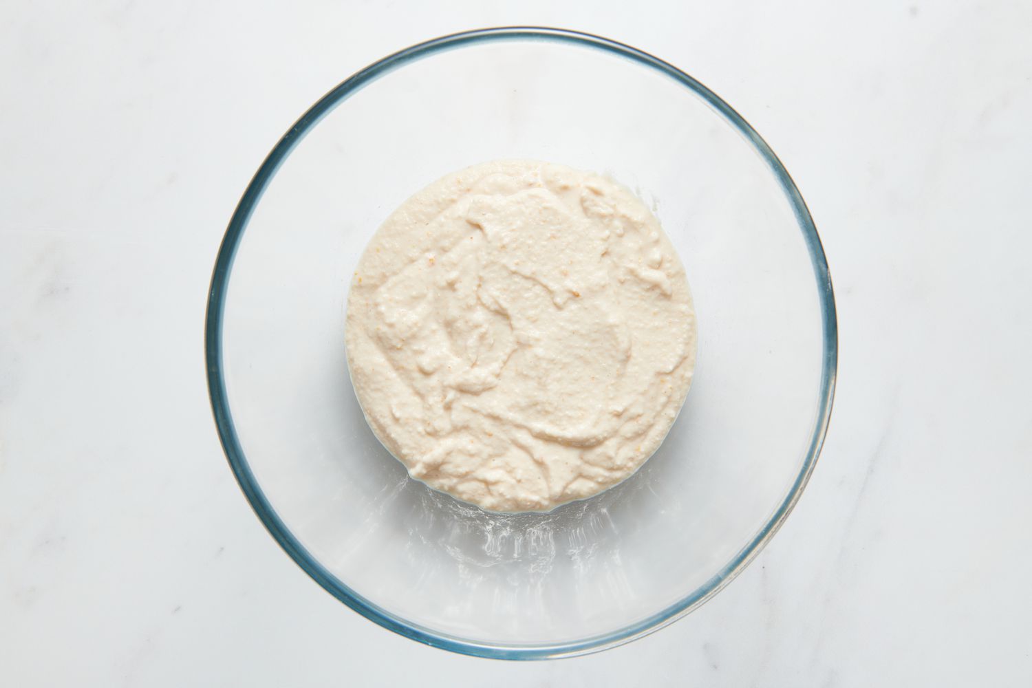 A large glass bowl of urad dal-fenugreek batter