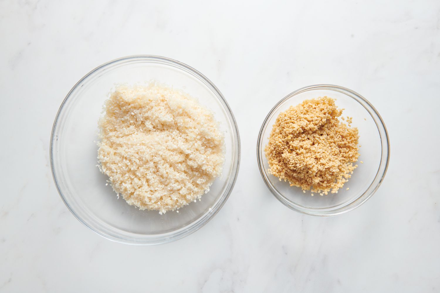A glass bowl of rinsed Sona Masuri and a glass bowl of rinses urad dal