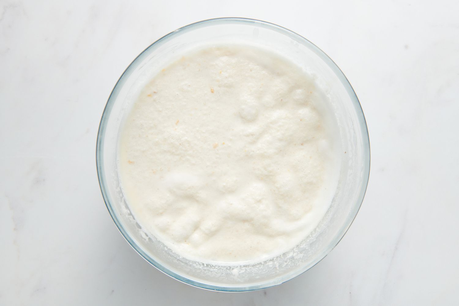 A large glass bowl of bubbly, fermented Sona Masuri-urad dal batter