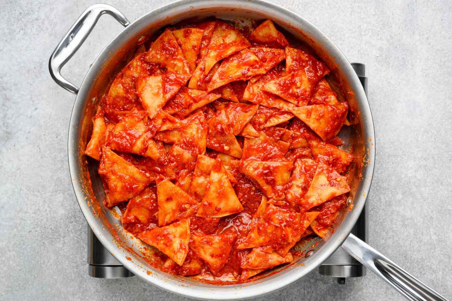 A pan of fried tortilla chips tossed in a chile-tomato sauce