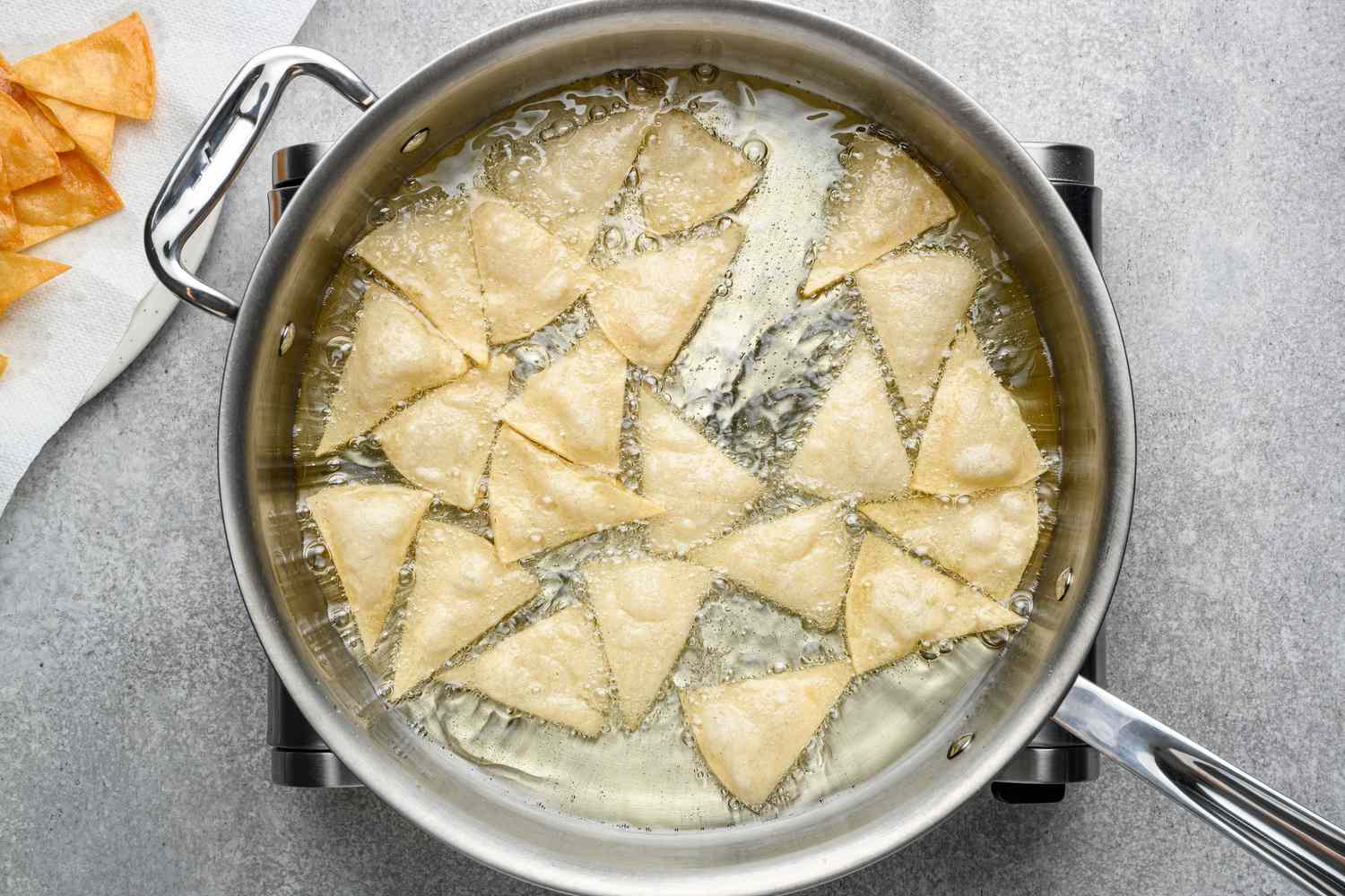 Wedges of tortillas frying in a pan of oil