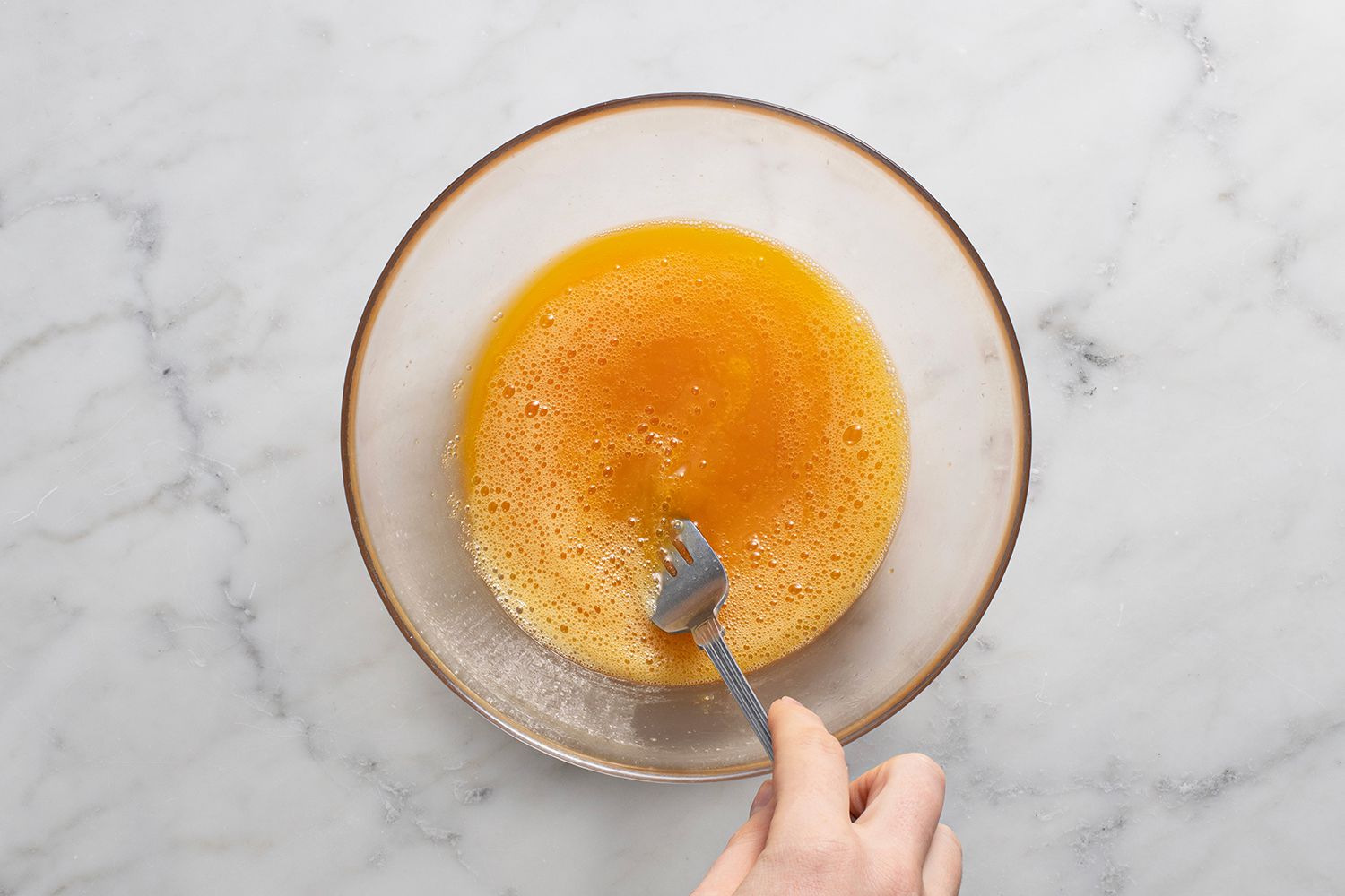 Eggs and salt in a glass bowl, stirred with a fork