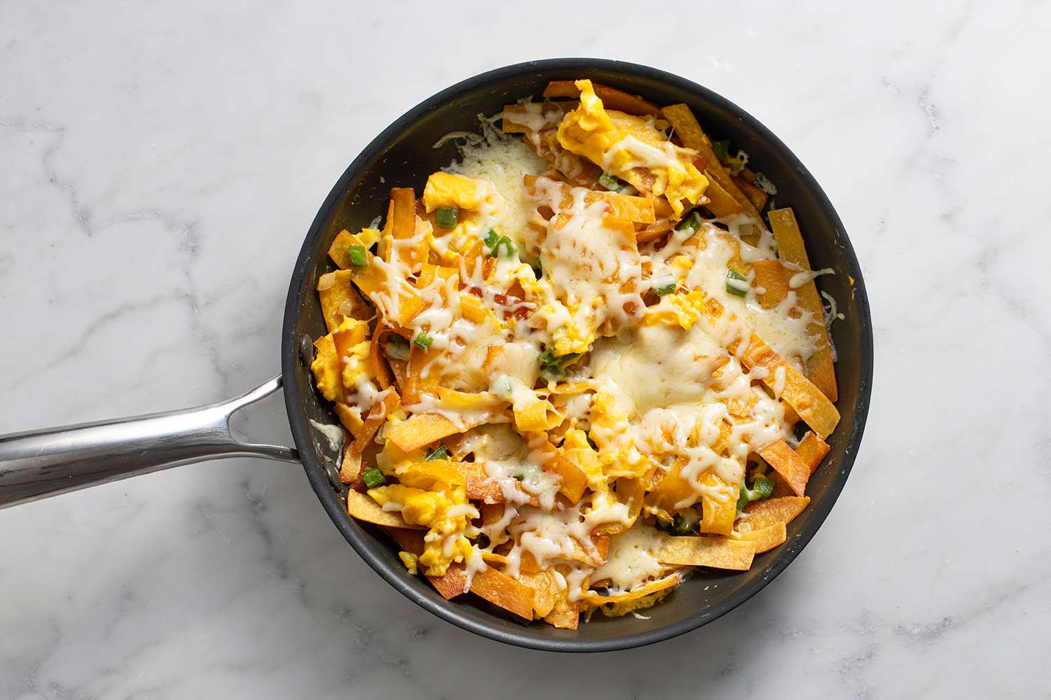 Melted cheese on top of the tortilla and eggs mixture in a pan