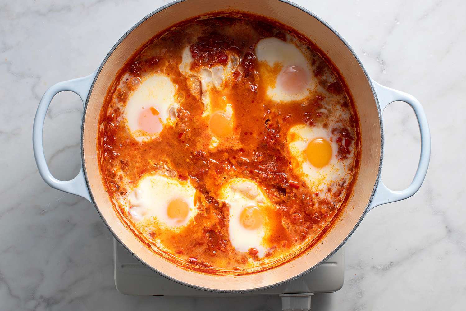 Eggs cooking in the tomato sauce in a pot on a burner