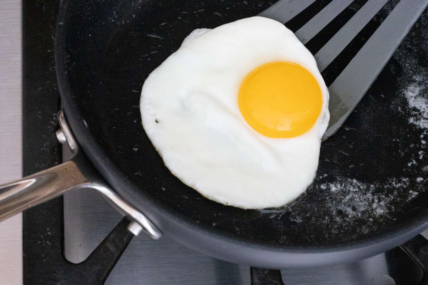 Espátula deslizando sob o ovo na frigideira