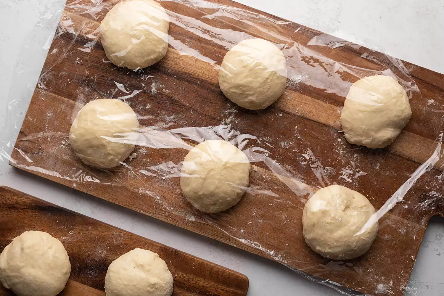 Porções redondas de massa cobertas com filme plástico