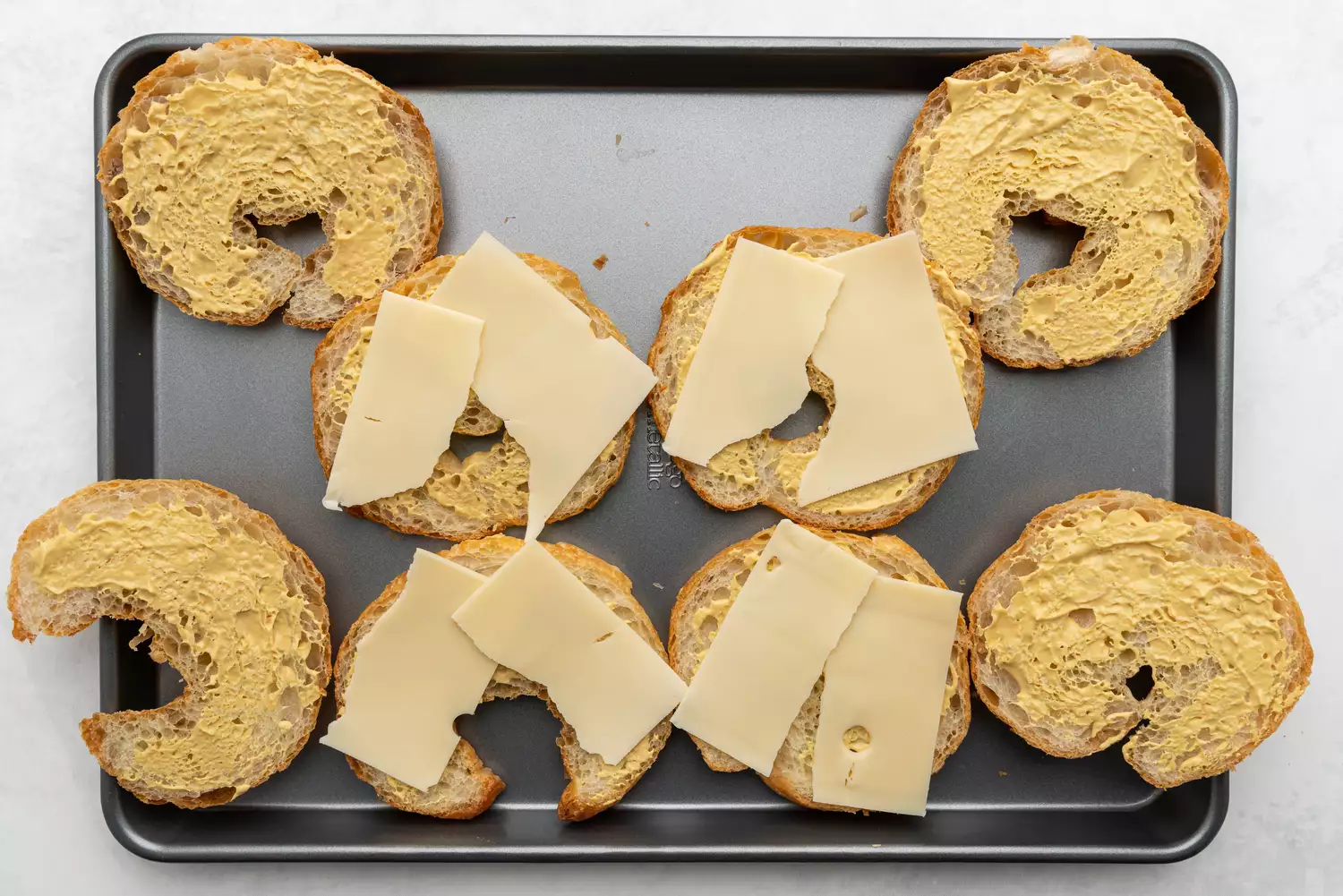 Metades de croissant cobertas com mostarda e queijo