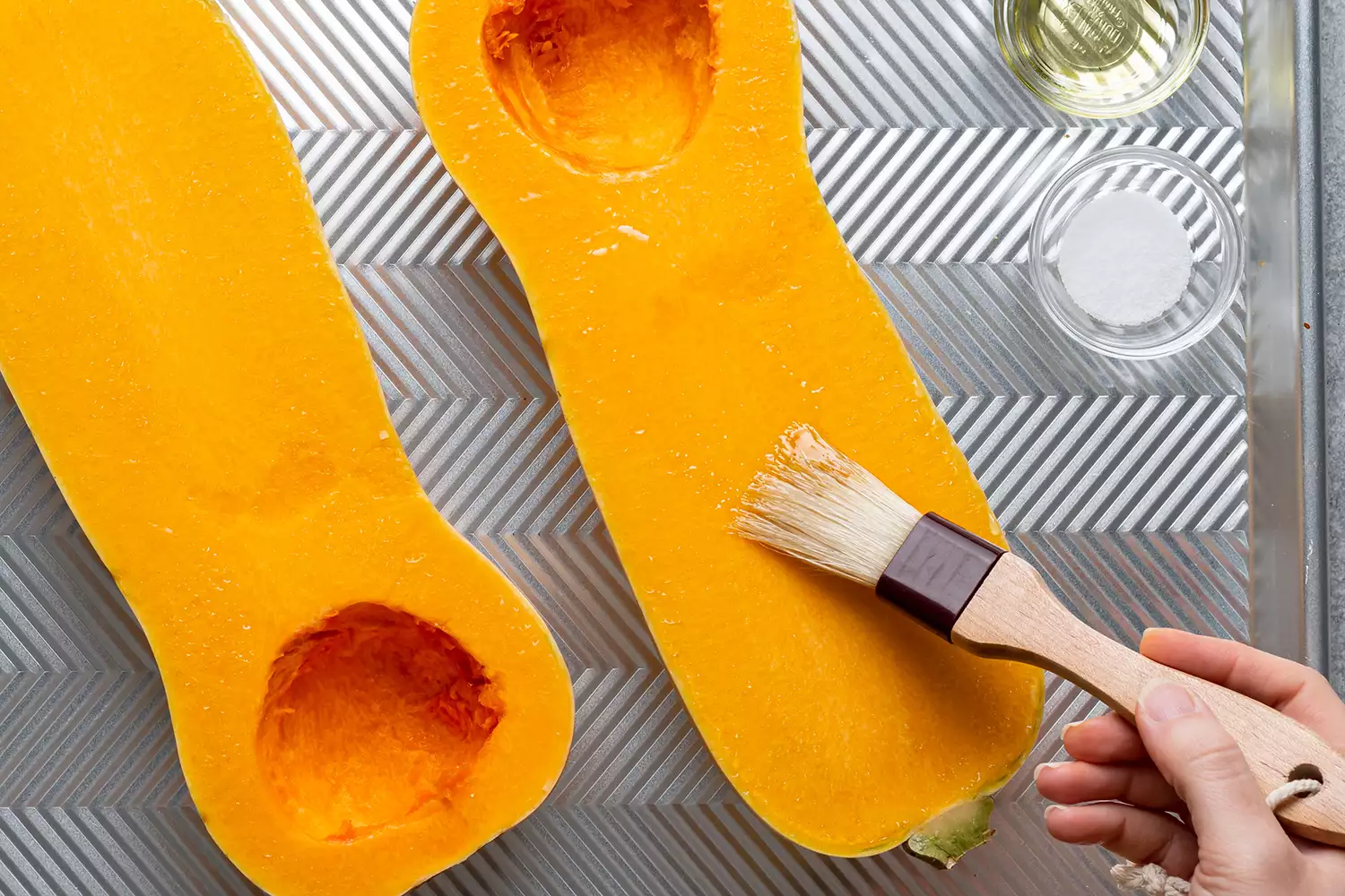 pincelando metades de abóbora com óleo de cozinha