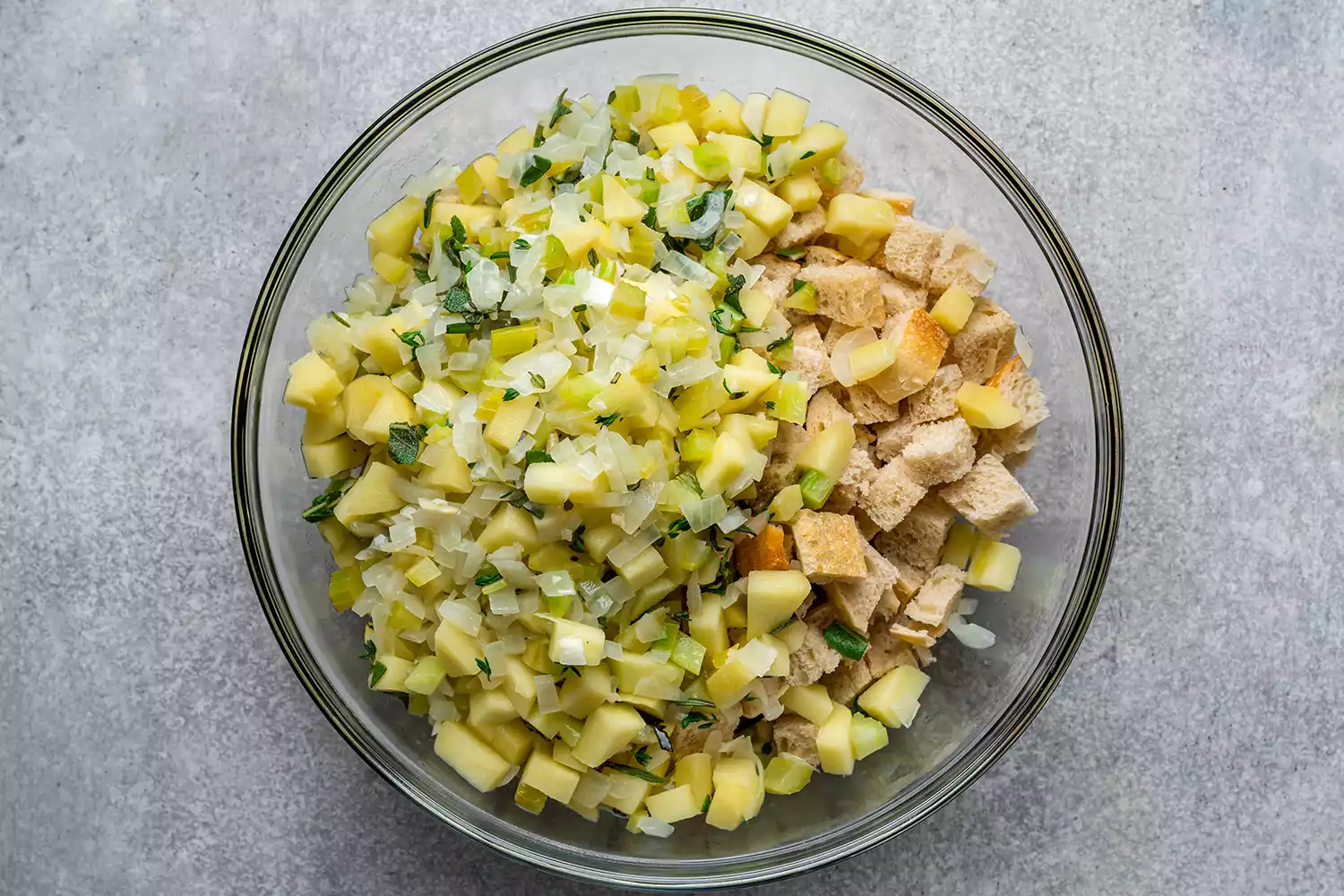 cebolas, aipo e maçãs cozidos em uma tigela com pão em cubos