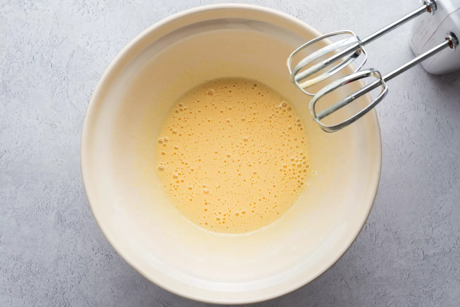 Bater as gemas e cream cheese até ficar cremoso