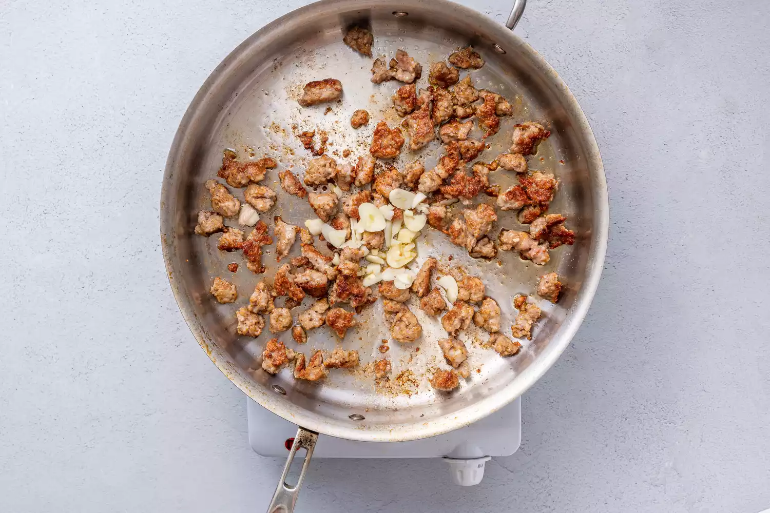 Alho e flocos de pimenta adicionados à panela com salsicha
