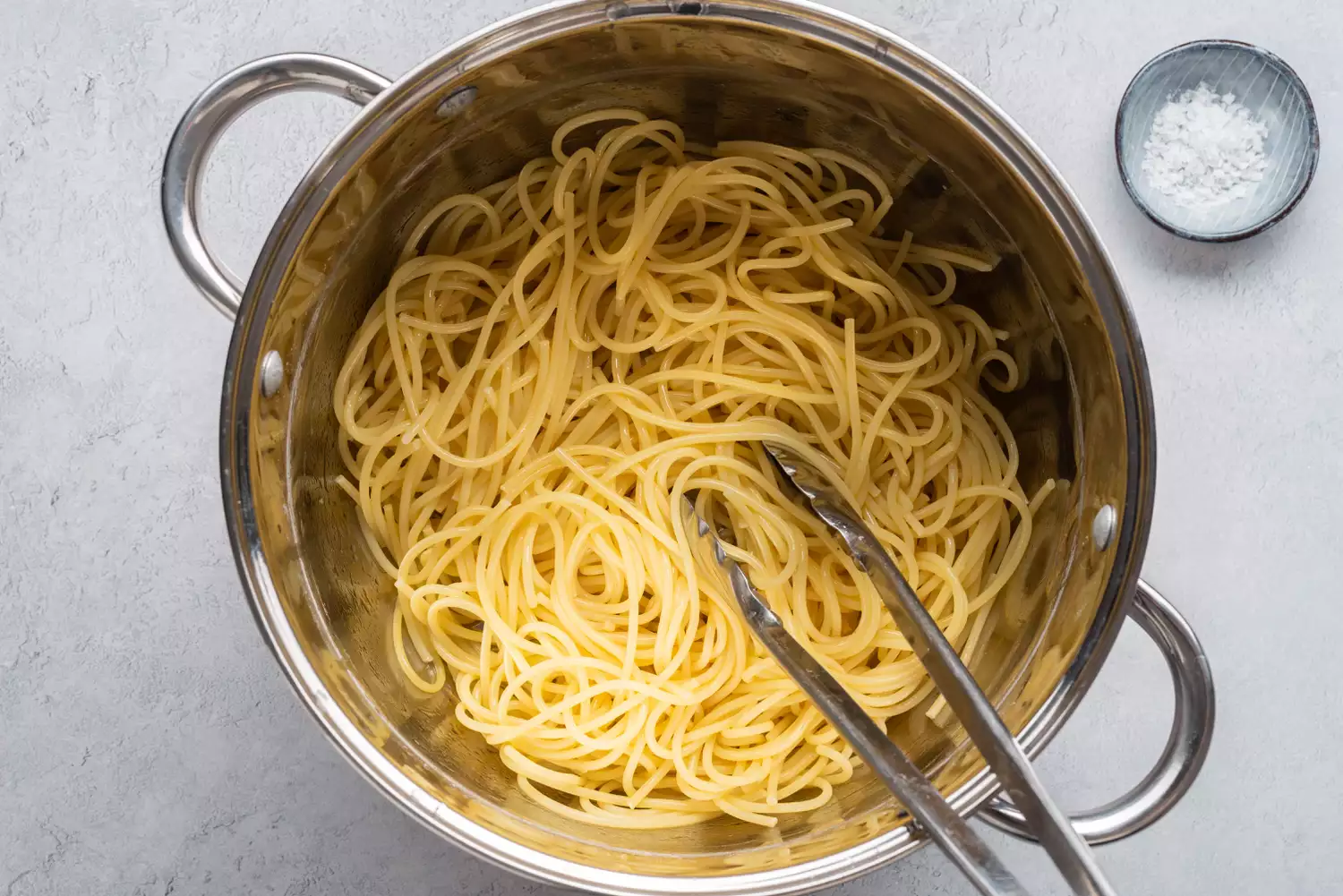 Espaguete cozido em uma panela com pegadores de metal