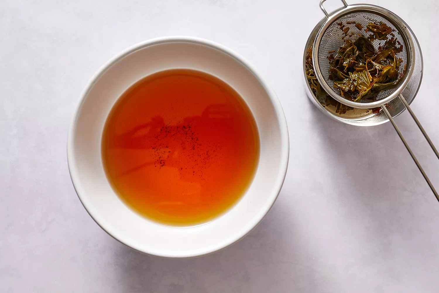 Chá oolong em uma tigela, com folhas de chá coadas ao lado