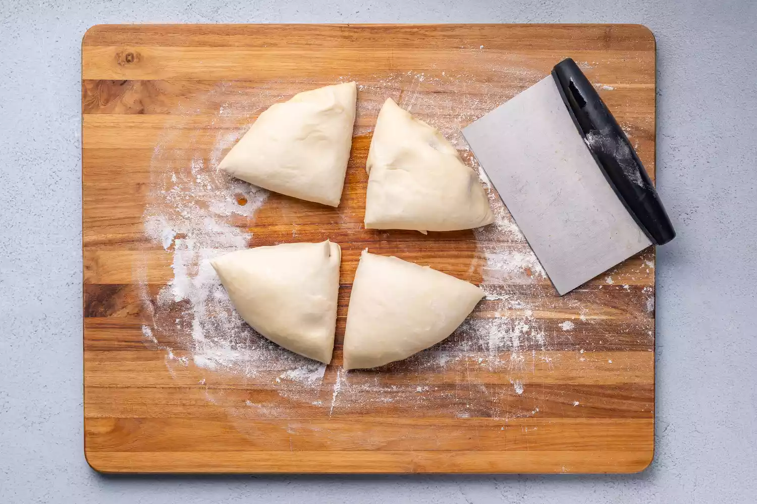 Quatro pedaços de massa em uma tábua enfarinada