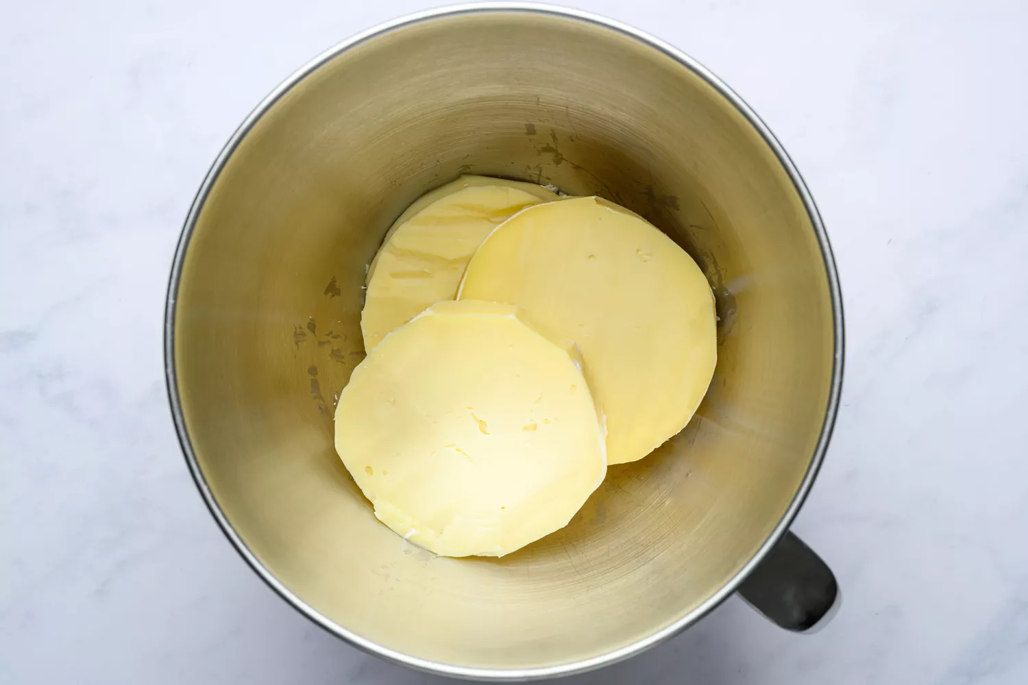 Three discs of brie with the rind removed, in a large mixing bowl