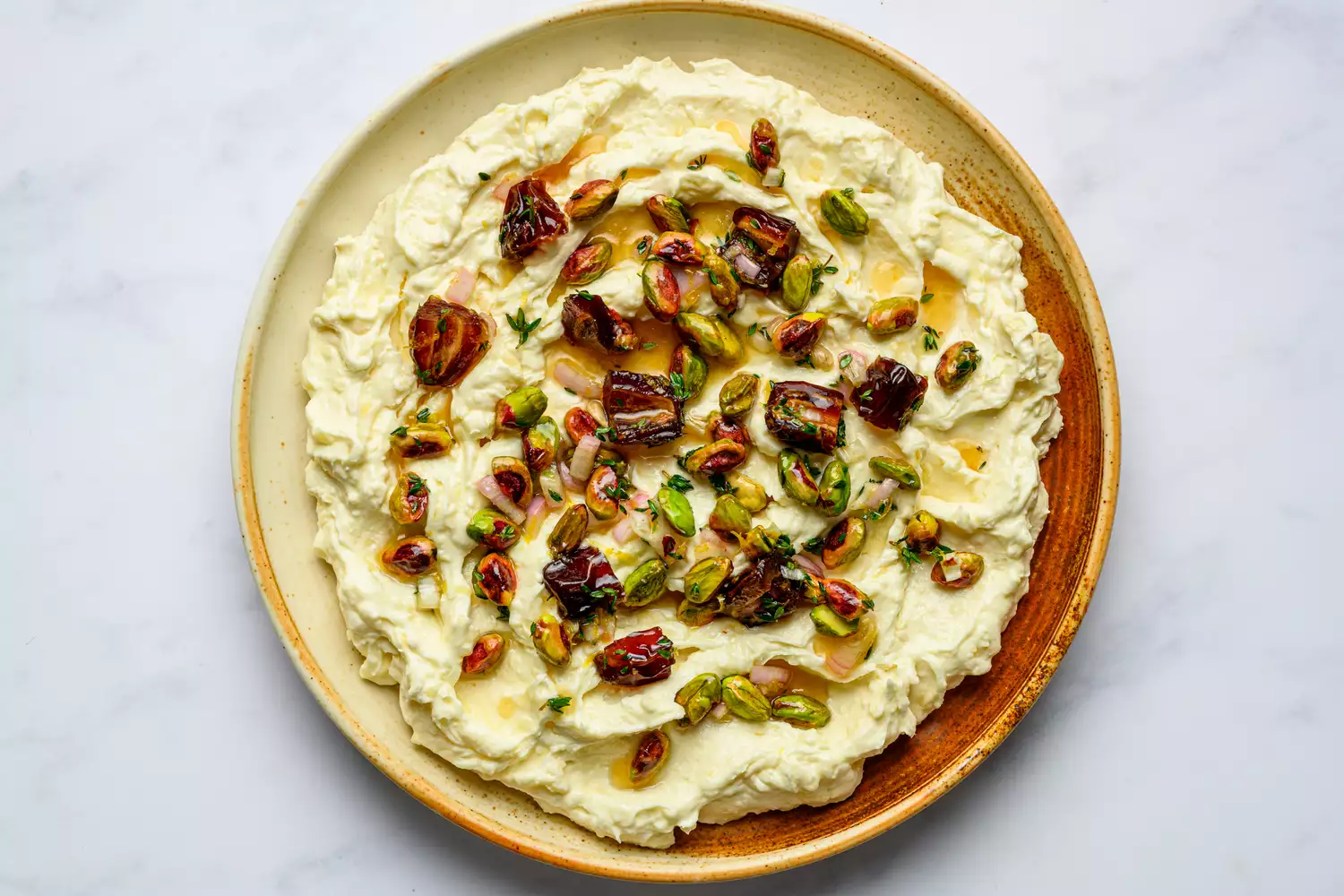 A large plate with whipped brie topped with fruit and nuts