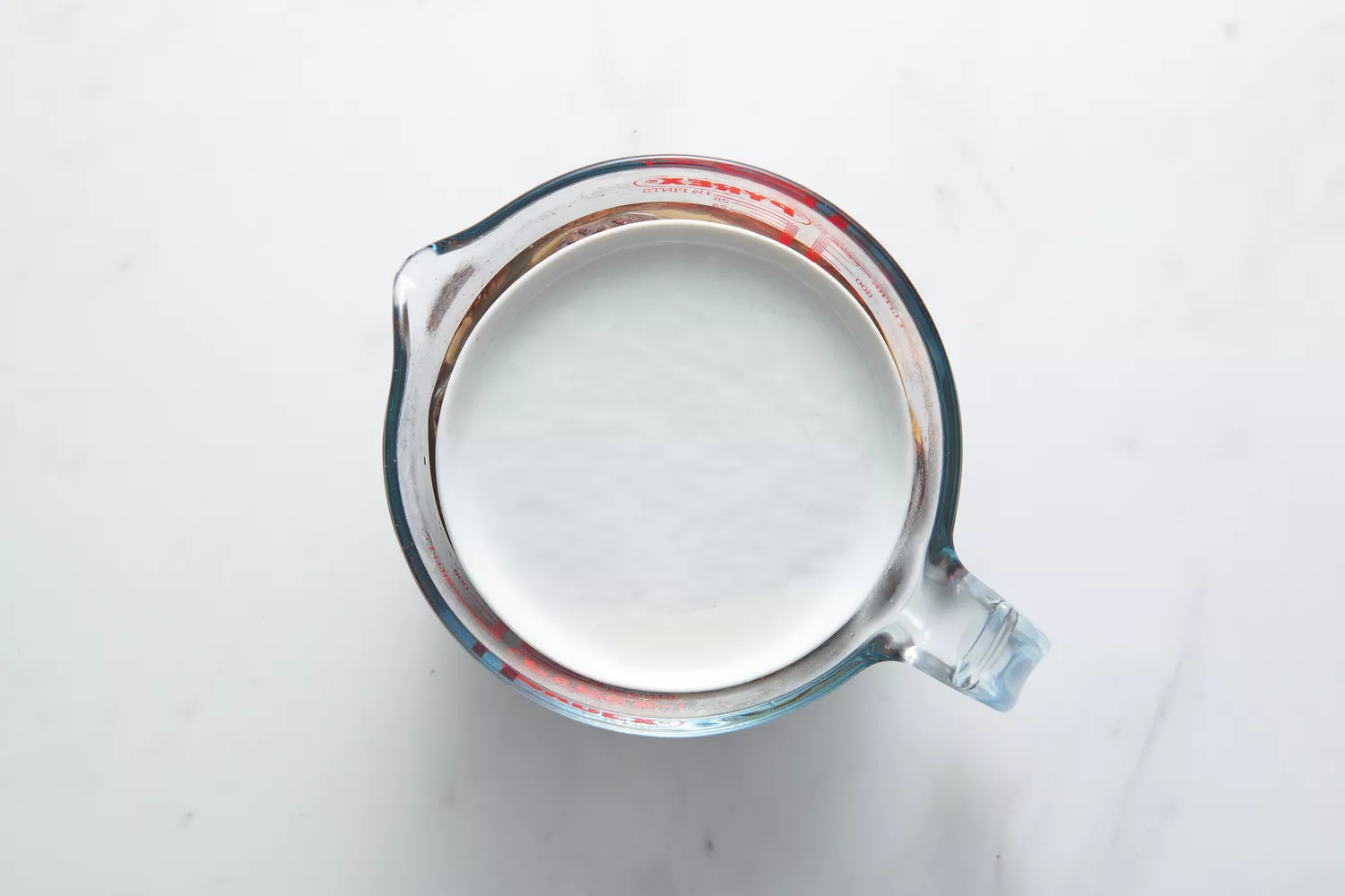 Um copo medidor com água e cogumelos shiitake, com um pequeno prato pesando os cogumelos