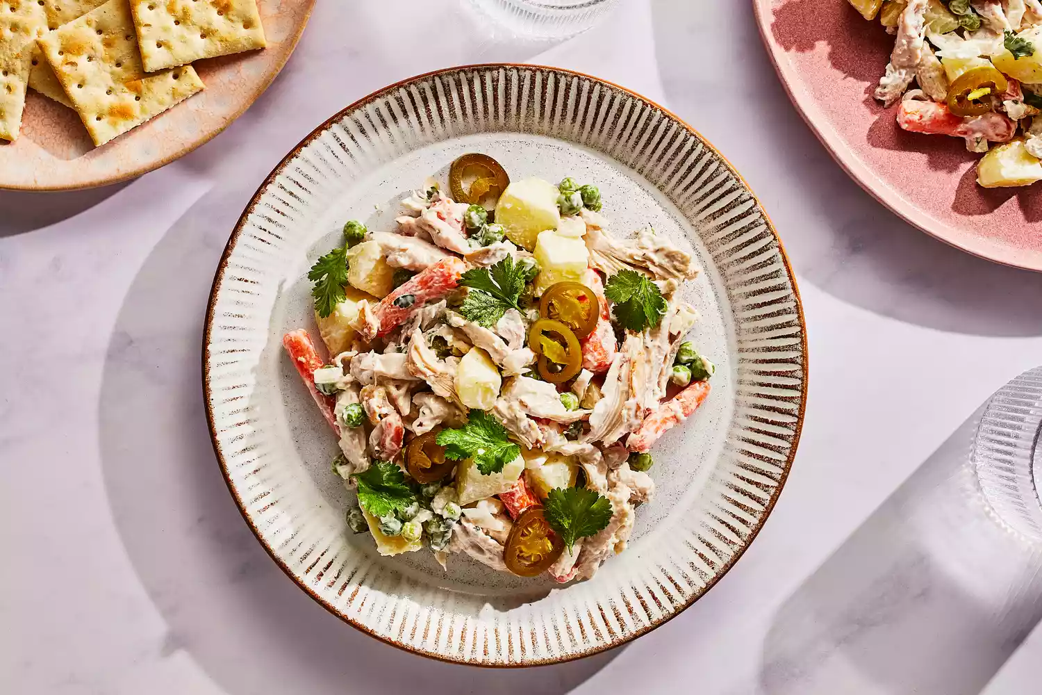 Um prato de salada de frango mexicana, servido com jalapeños em conserva e biscoitos