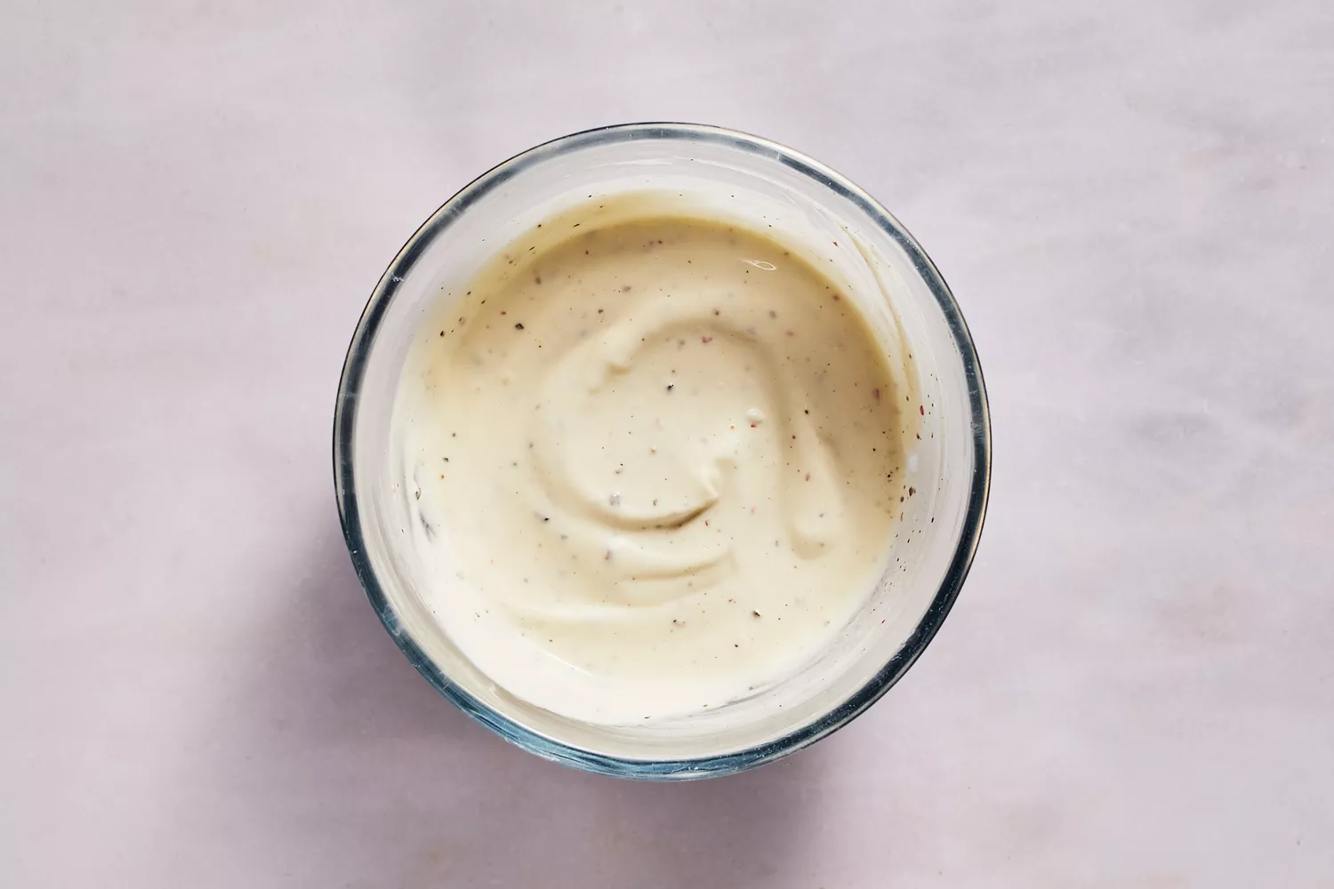 Uma tigela pequena de maionese, crema mexicana, suco de limão, sal e pimenta do reino