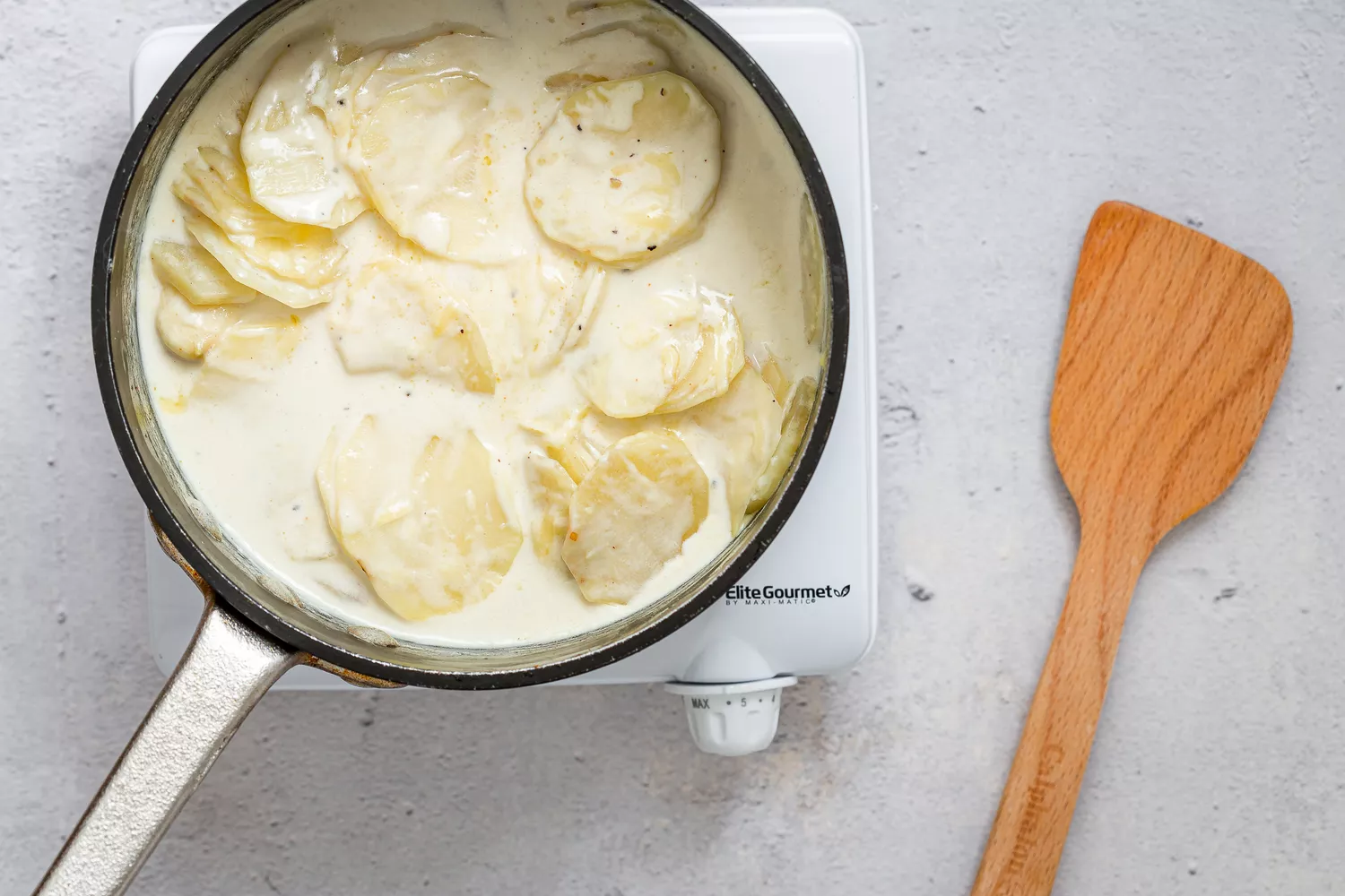 Batatas em um molho espesso de creme e leite em uma panela