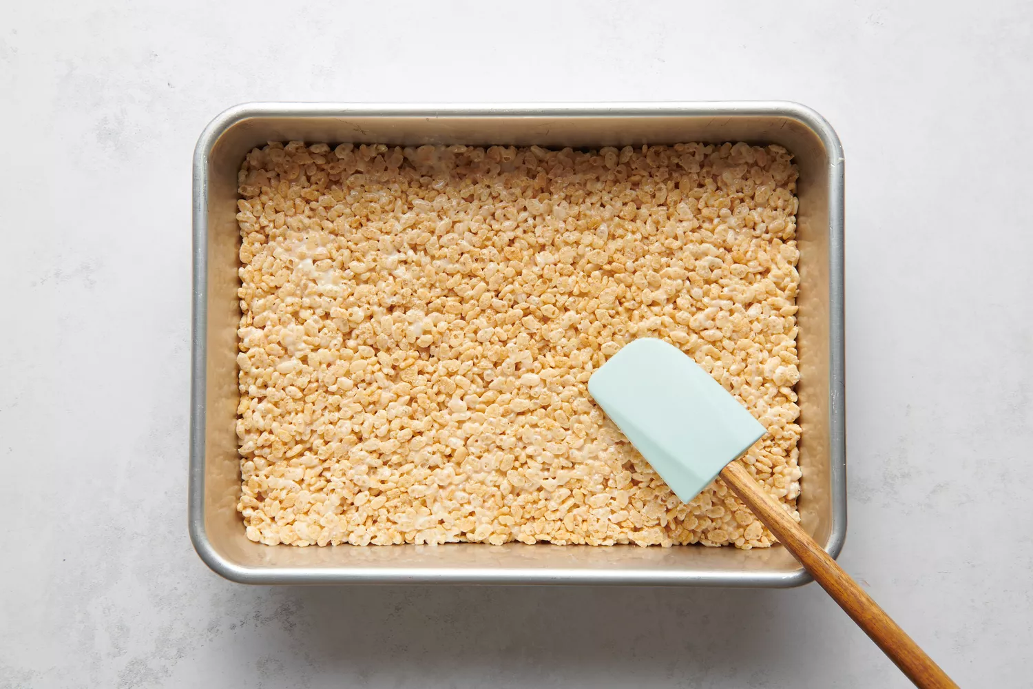 Uma forma de 9 x 13 com uma camada de mistura de cereal de arroz puffado e marshmallow