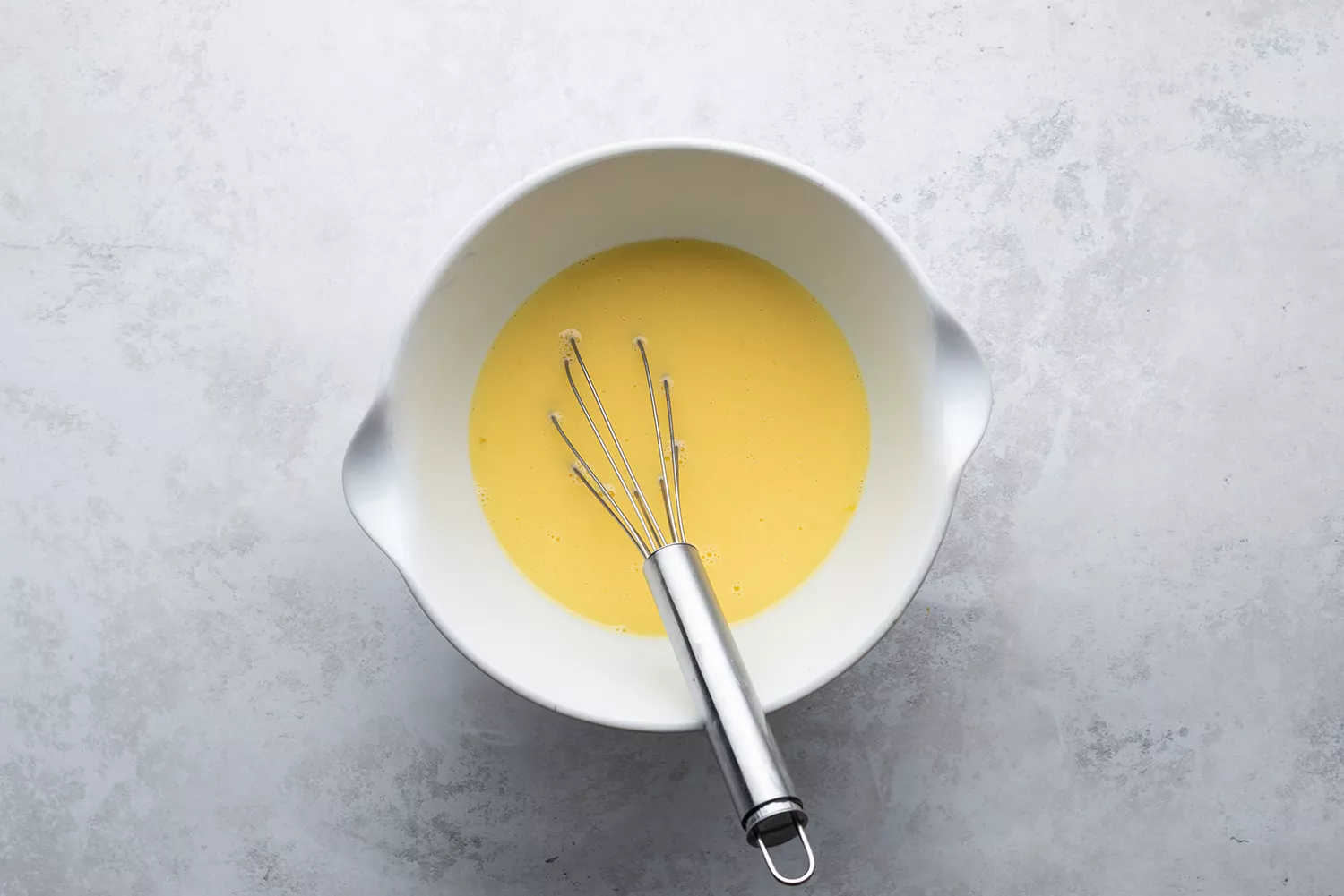 Mistura de leite e ovos em uma tigela com batedor