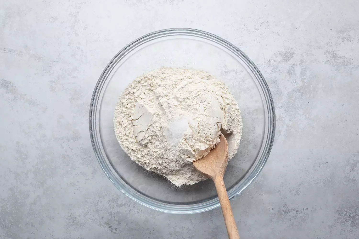 Farinha e sal em uma tigela de vidro com colher de madeira