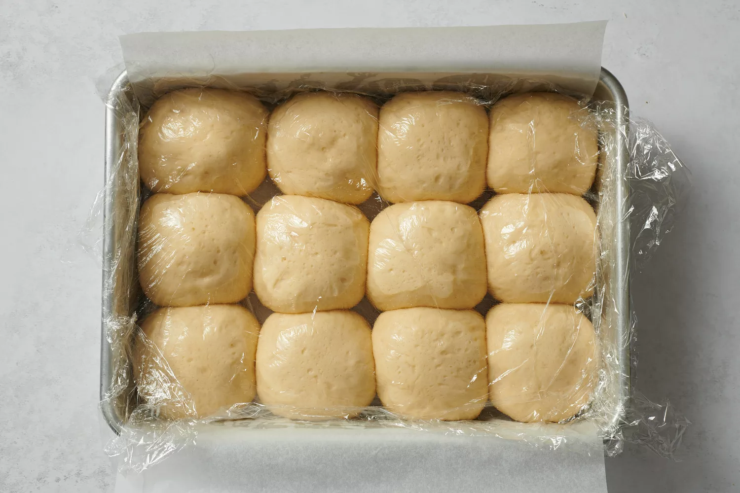 Bolhas de massa cobertas com filme plástico em uma assadeira