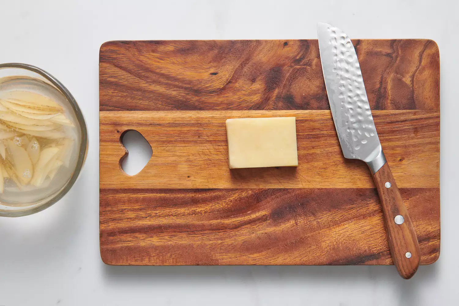 Uma tábua de corte com uma pilha de batatas fatiadas cortadas em um retângulo