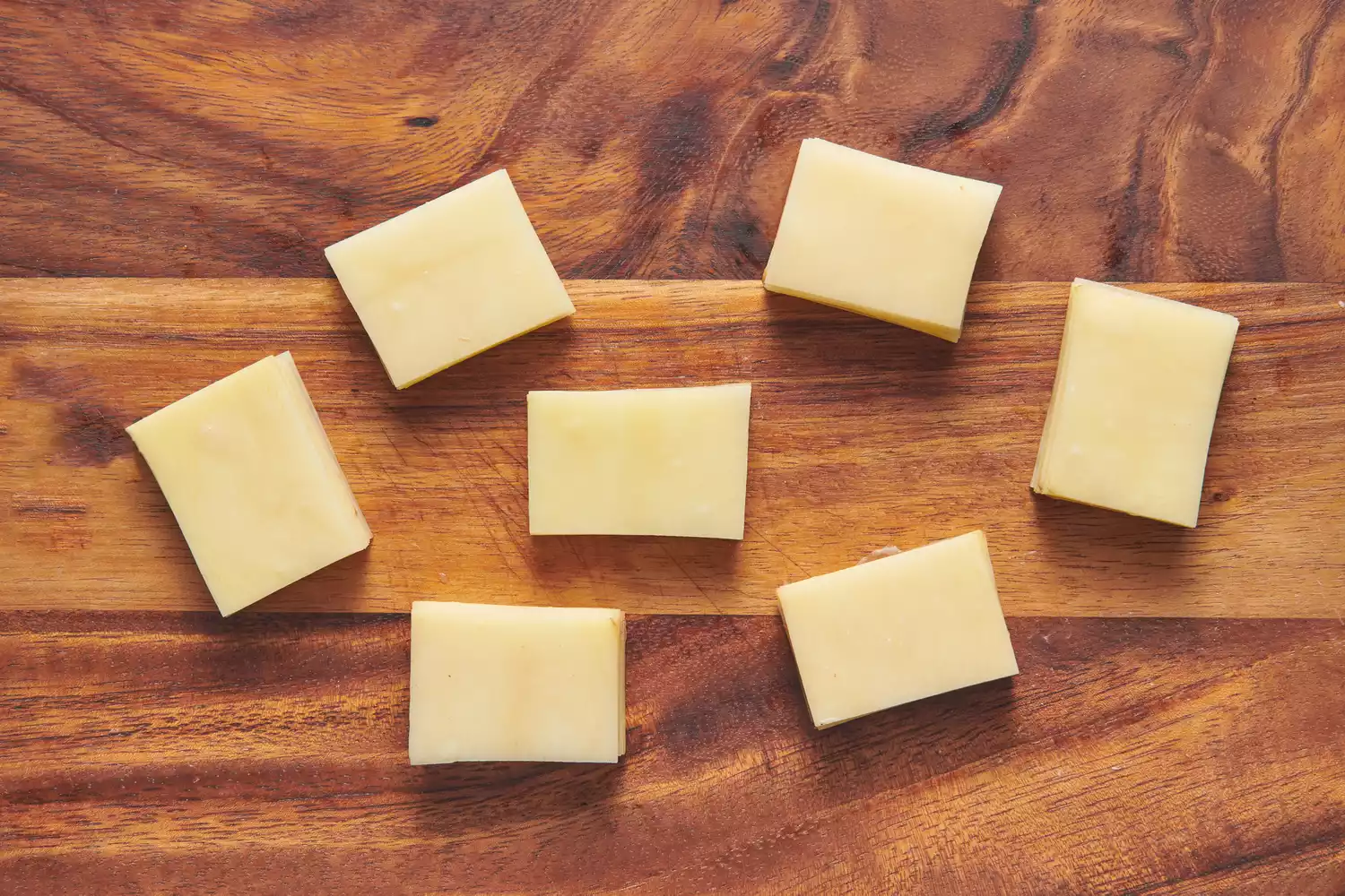 Uma tábua de corte com 7 pequenas pilhas de batatas fatiadas dispostas diretamente uma sobre a outra