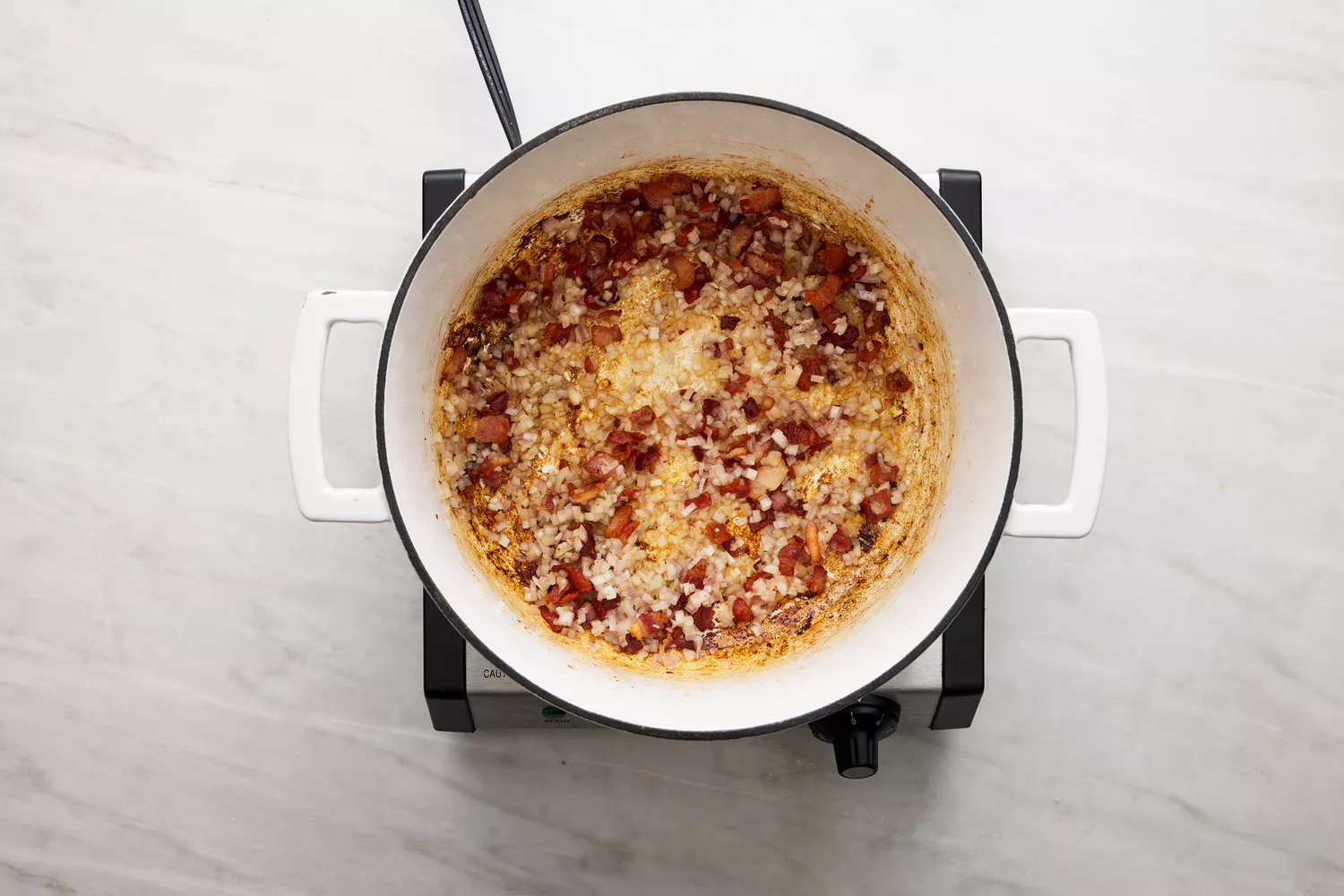 bacon e cebolas cozinhando na panela holandesa