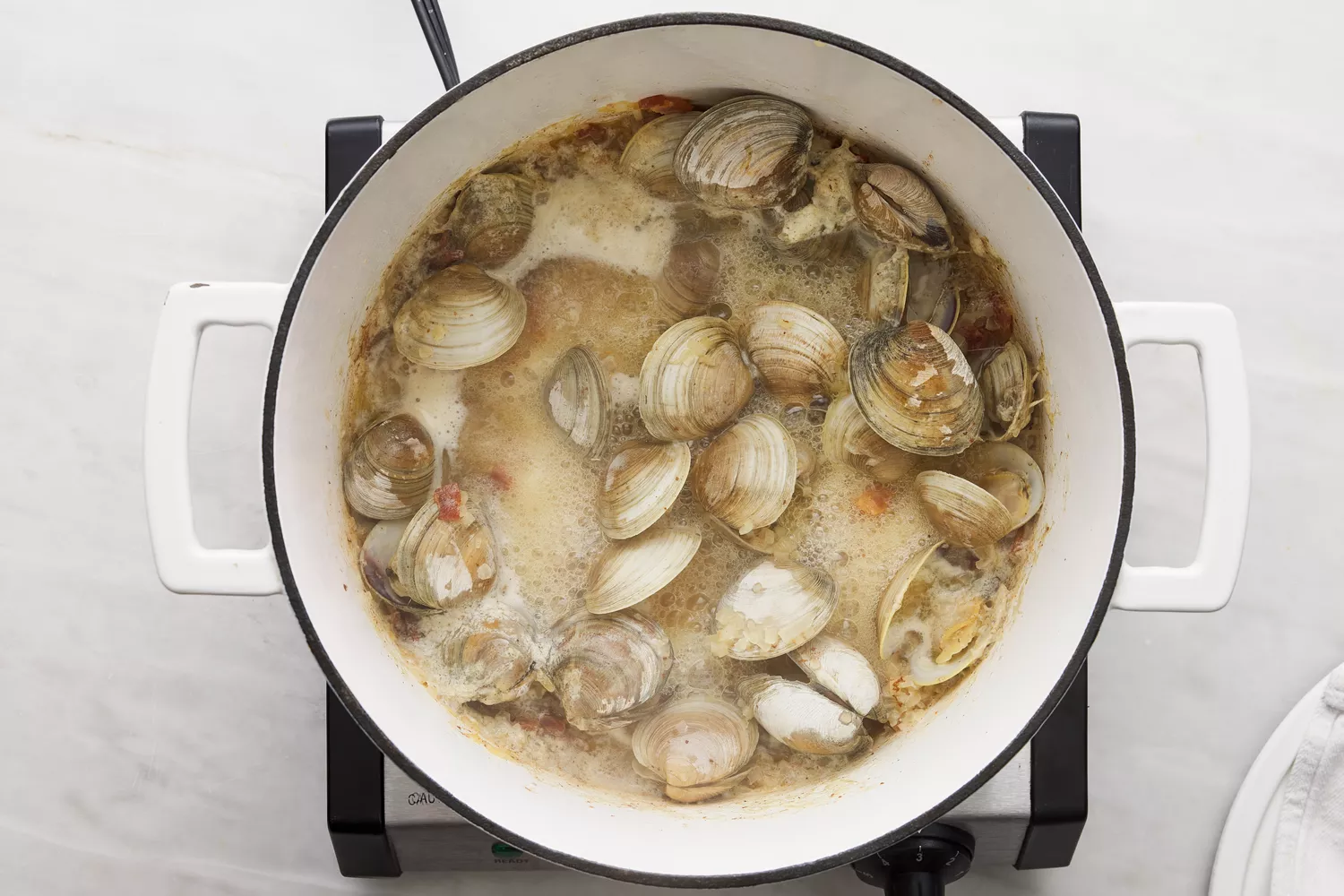 vinho e moluscos adicionados à panela holandesa com bacon e cebolas