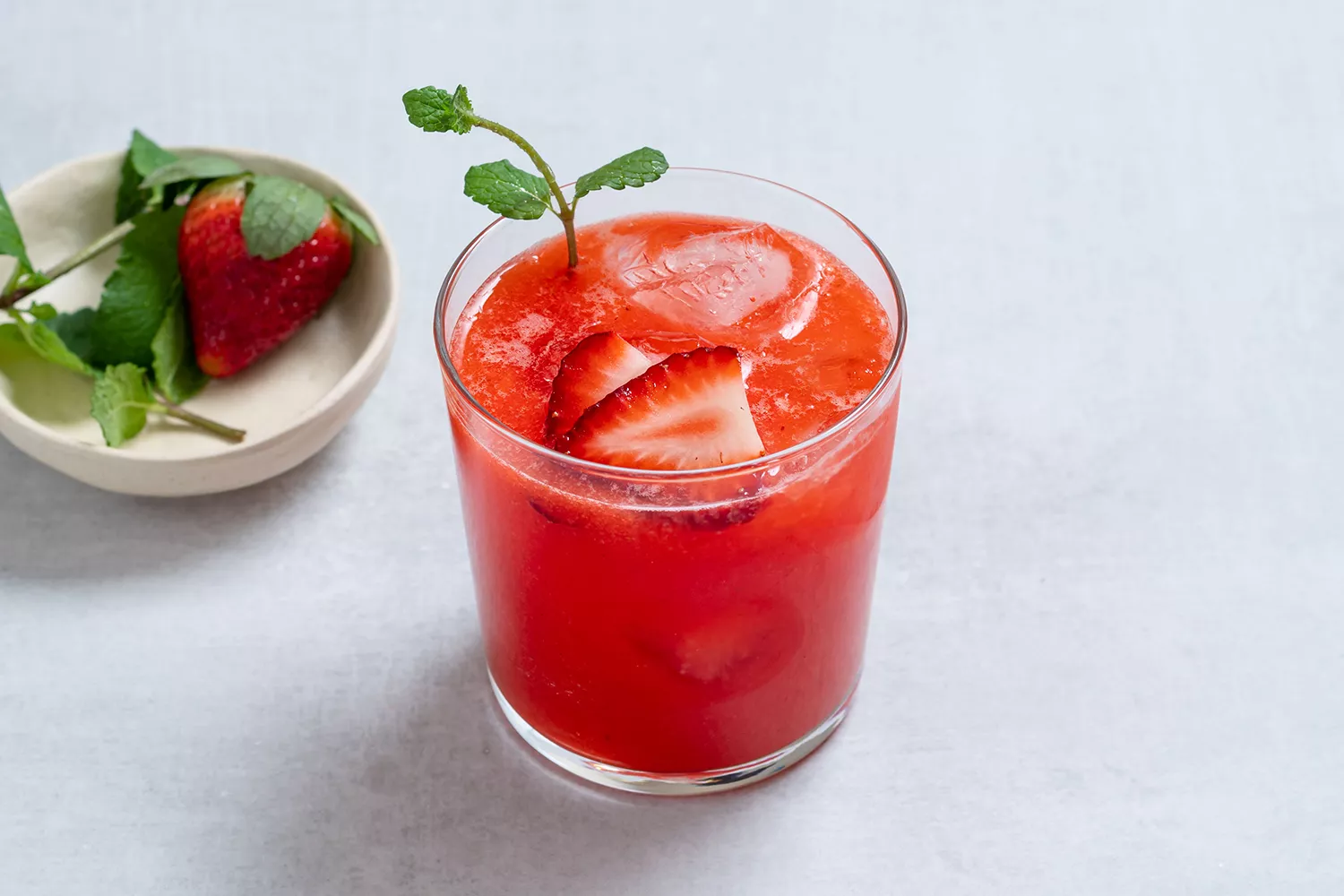 Limonada de morango em um copo, decorada com hortelã fresca e morangos fatiados