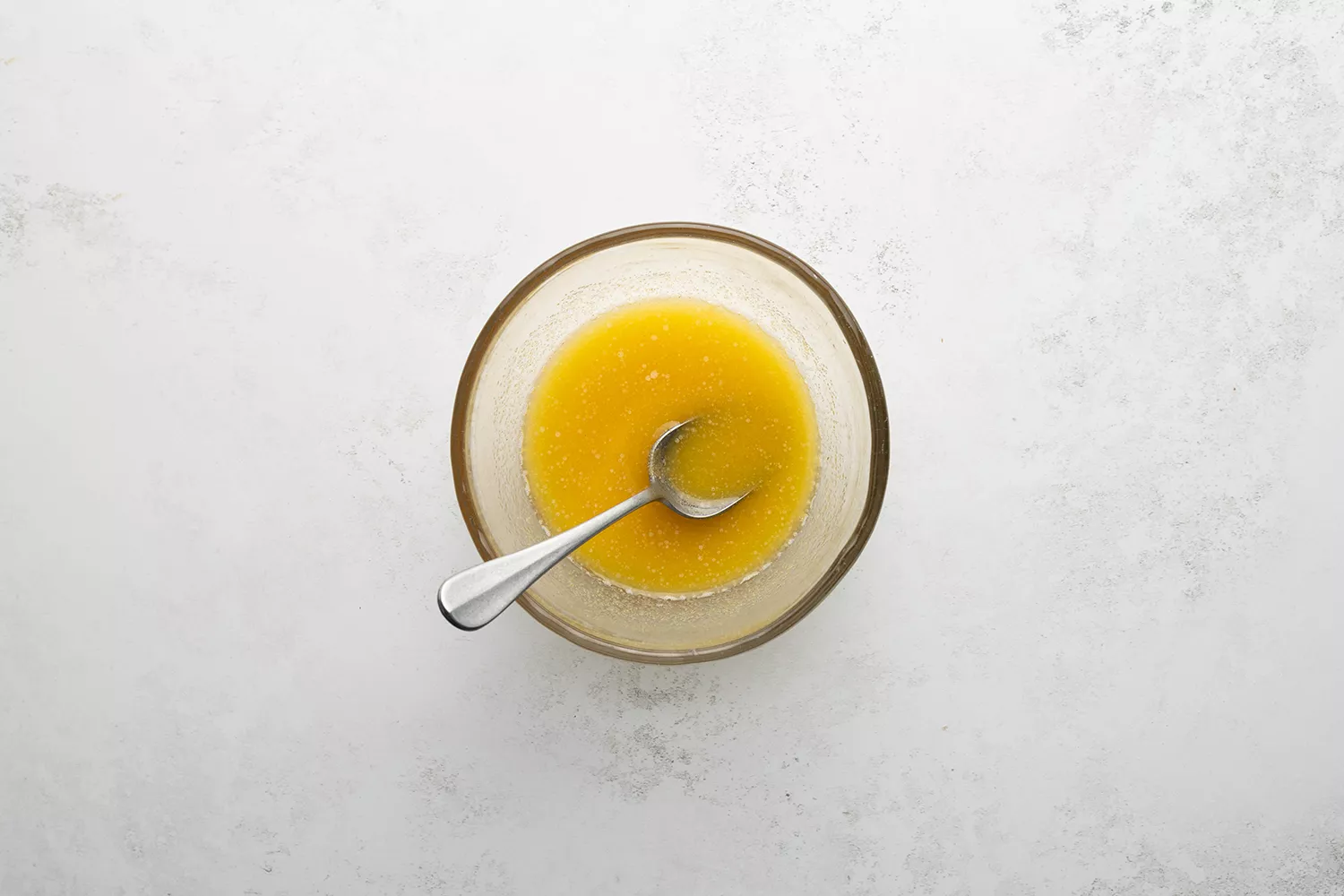 Manteiga derretida e alho em pó em uma tigela com uma colher