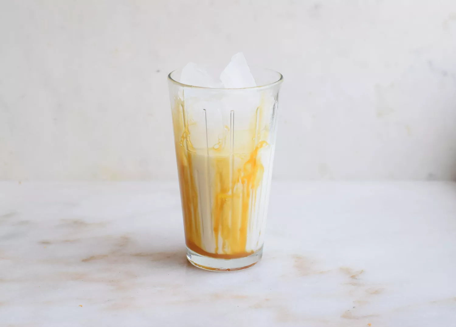 Gelo, leite e calda de caramelo em um copo