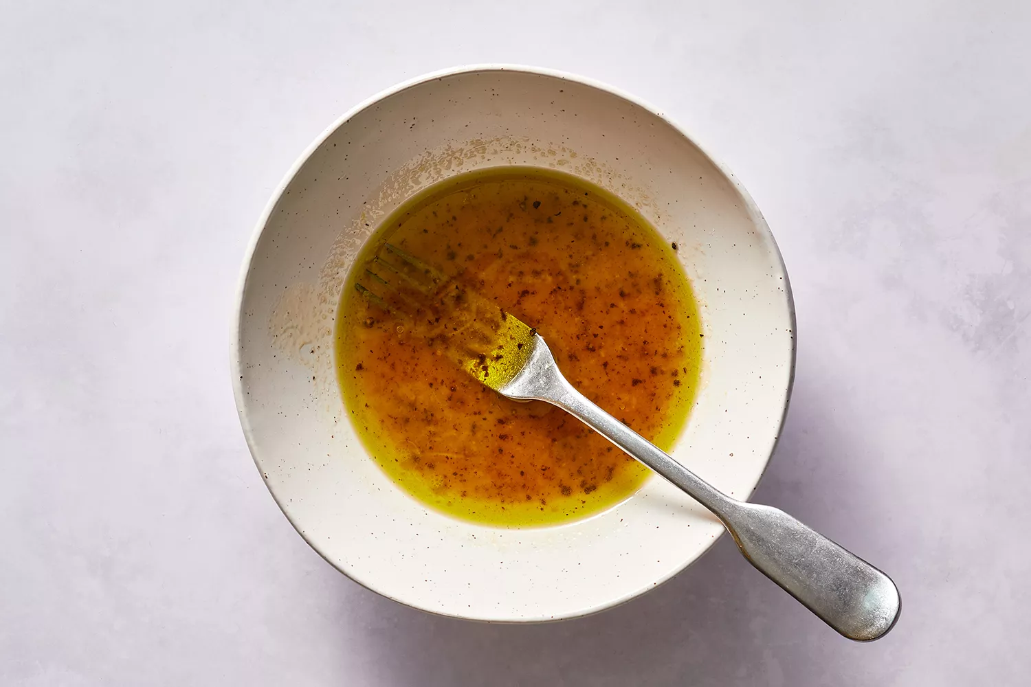 Uma tigela pequena com um garfo misturando o molho de salada cítrica de mel