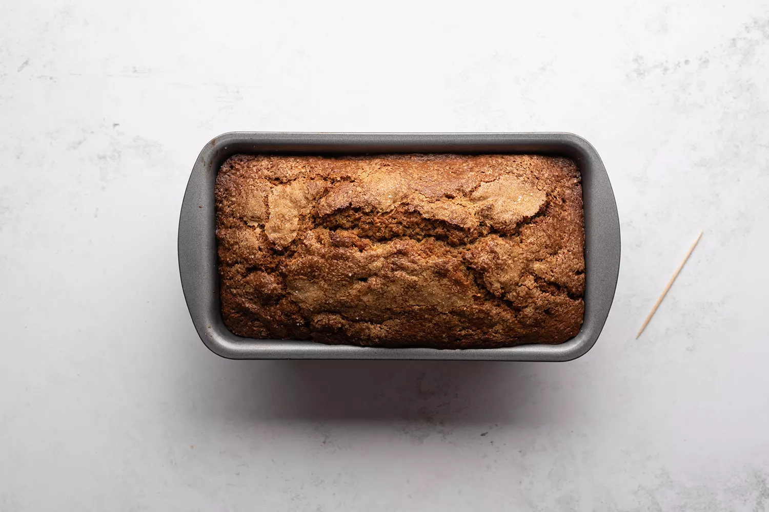 Pão de canela Assado em uma forma de pão, ao lado de um palito