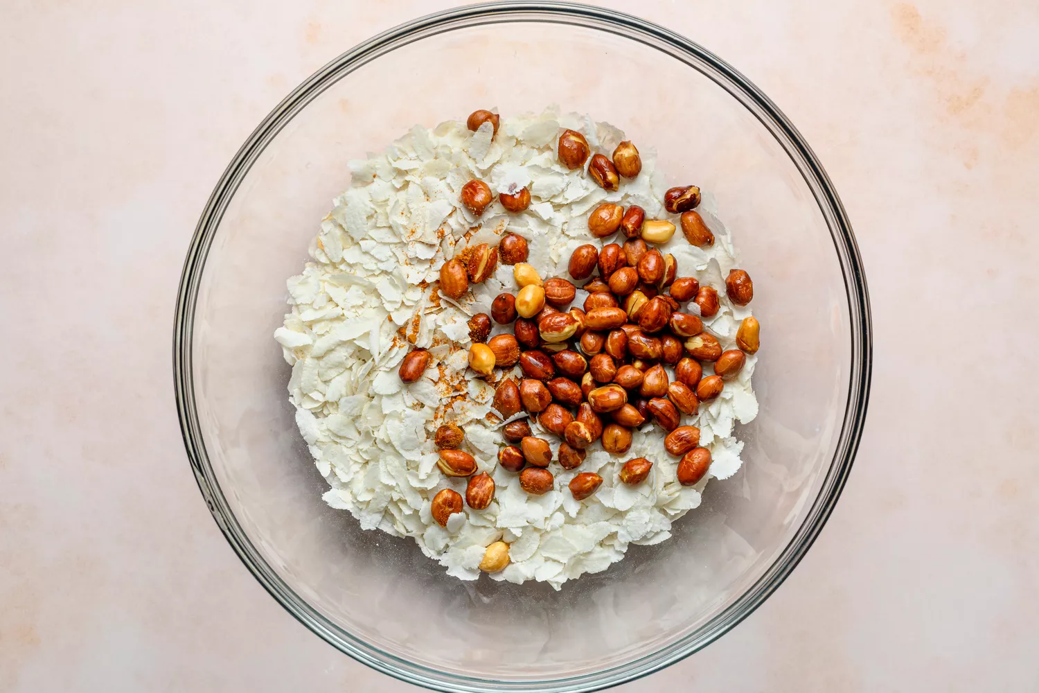 Uma grande tigela de poha torrado coberta com cúrcuma em pó, sal fino e amendoins crocantes
