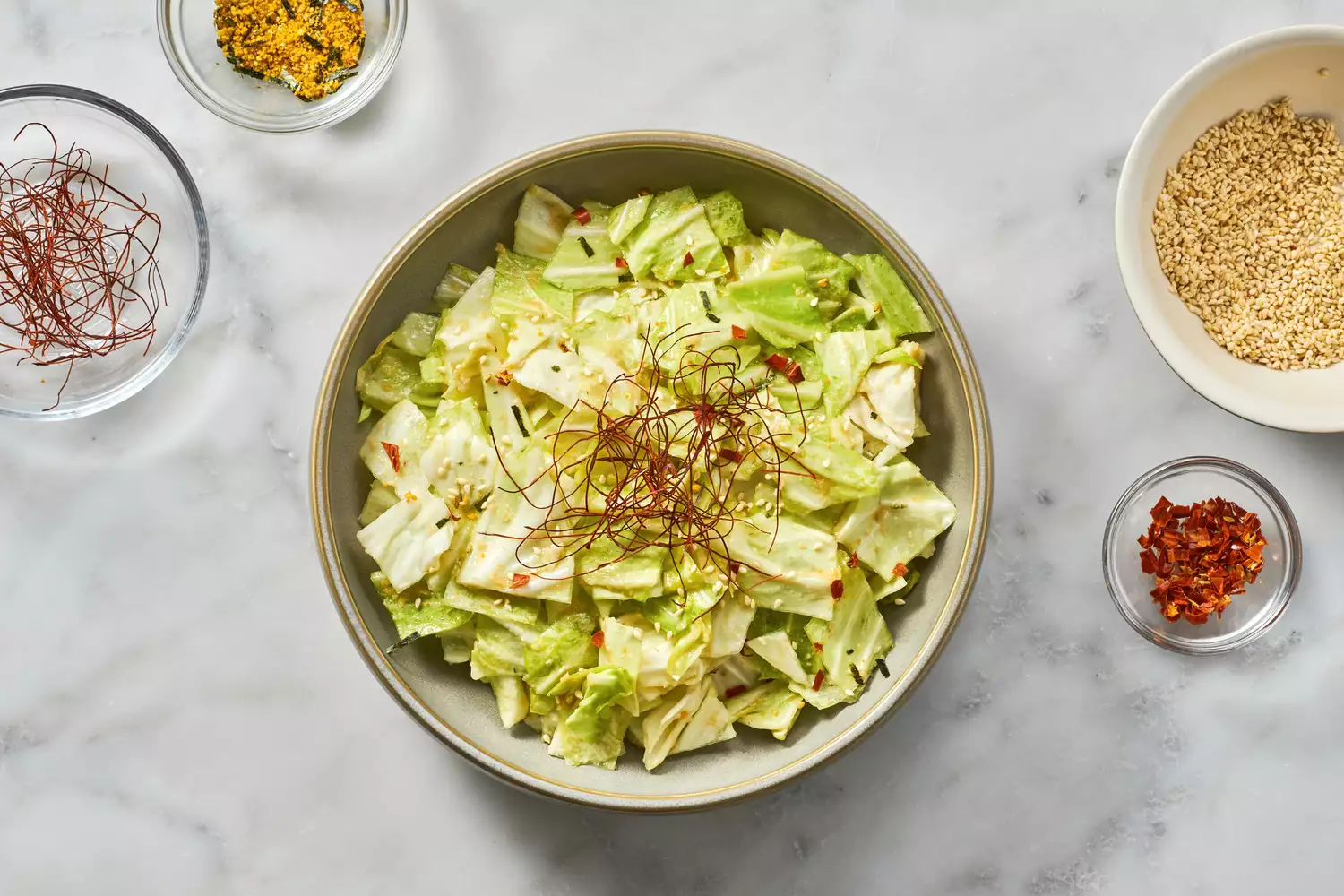 Uma grande tigela de yamitsuki (repolho viciante), decorada com pimentões secos picados, fios de pimenta, furikake e sementes de gergelim torradas