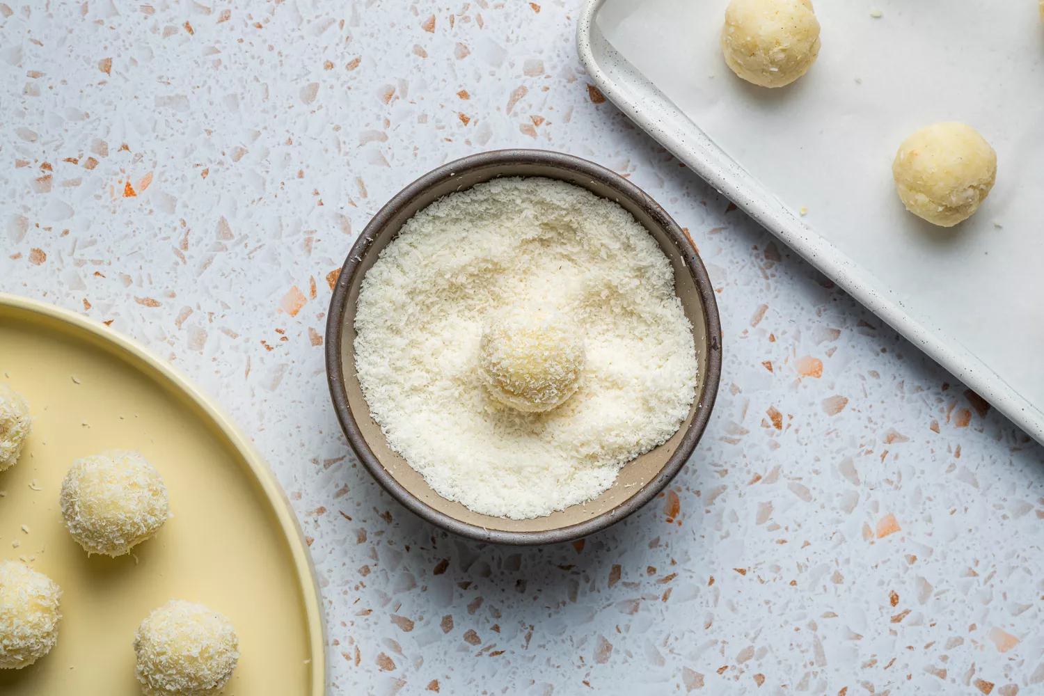 Uma tigela pequena de coco sem açúcar com uma bola de massa do laddu de coco dentro