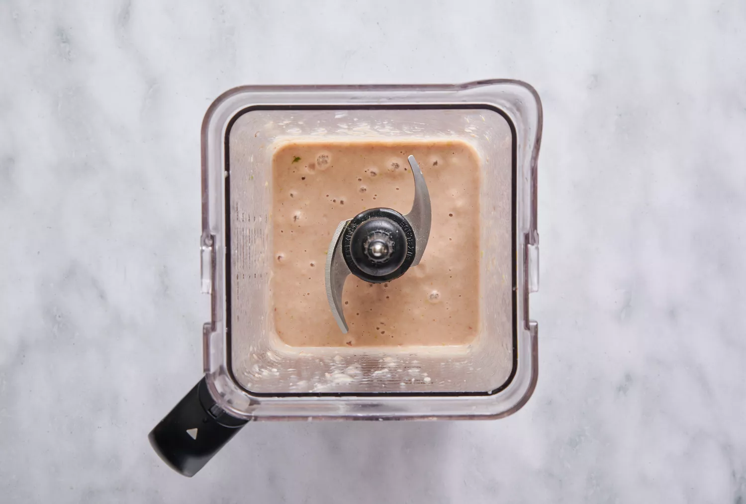 Um liquidificador com purê de feijão pinto, água, alho, cebola e pimenta serrano