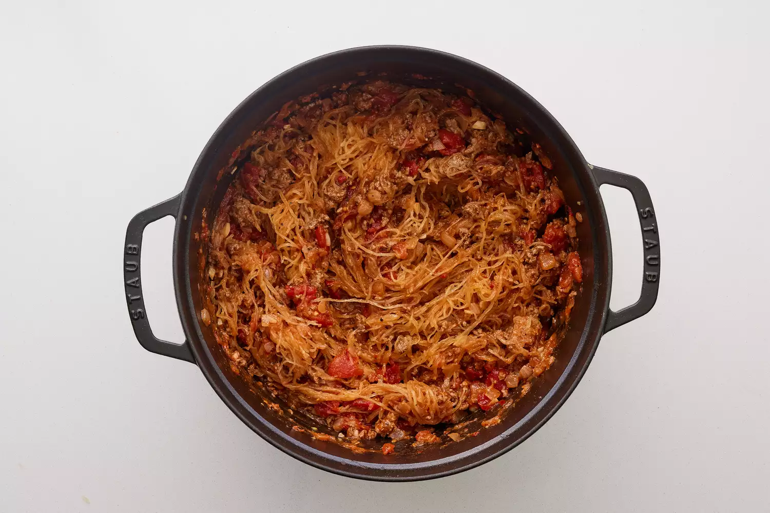 Uma panela de ferro com abóbora espaguete cozida adicionada à mistura de tomate e carne moída