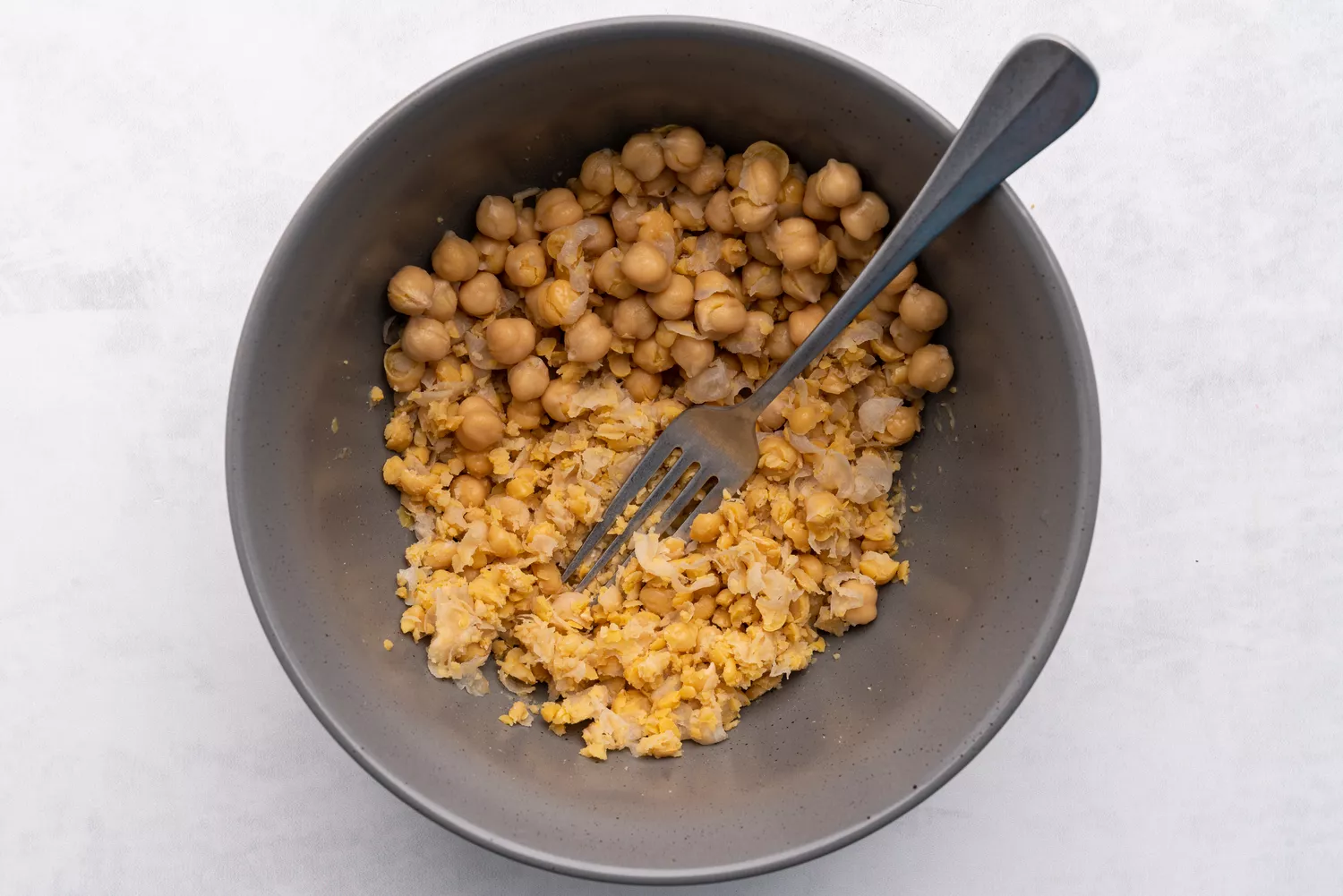 Grão-de-bico sendo amassado com um garfo em uma tigela