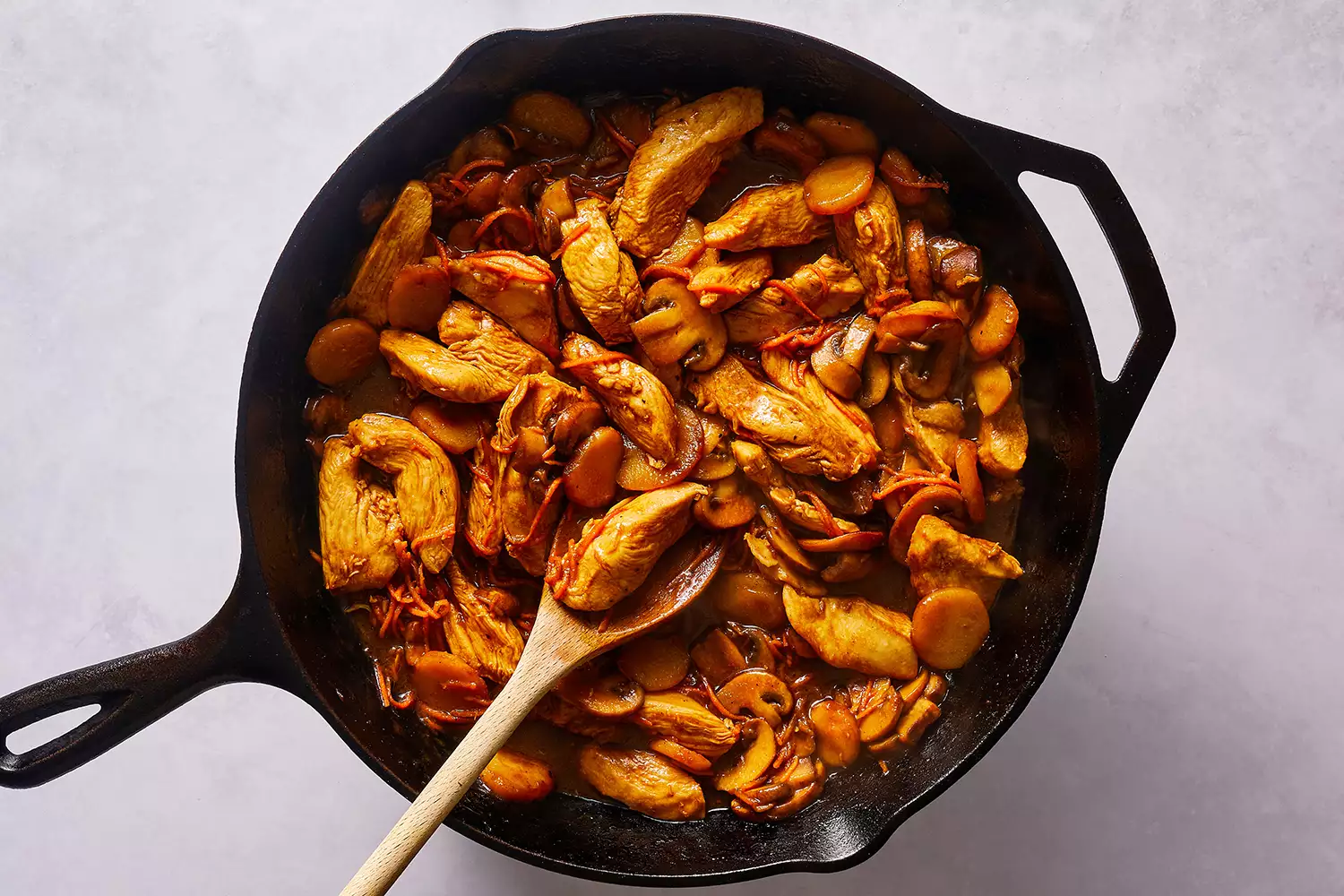 Moo Goo Gai Pan (Mah Gu Gai Pan) em uma frigideira de ferro fundido, com uma colher de madeira