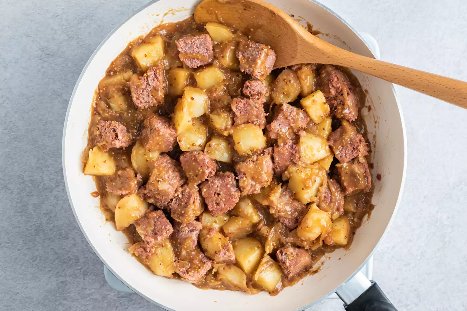 Carne de peito, batatas e cebolas em uma frigideira grande