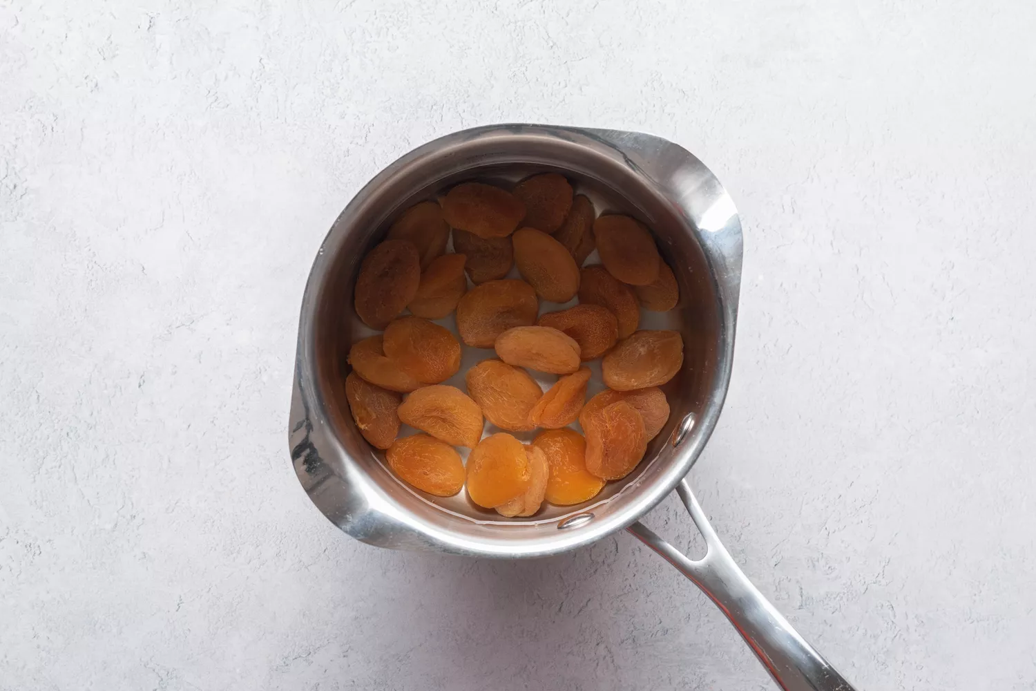 damascos secos em uma panela pequena com água