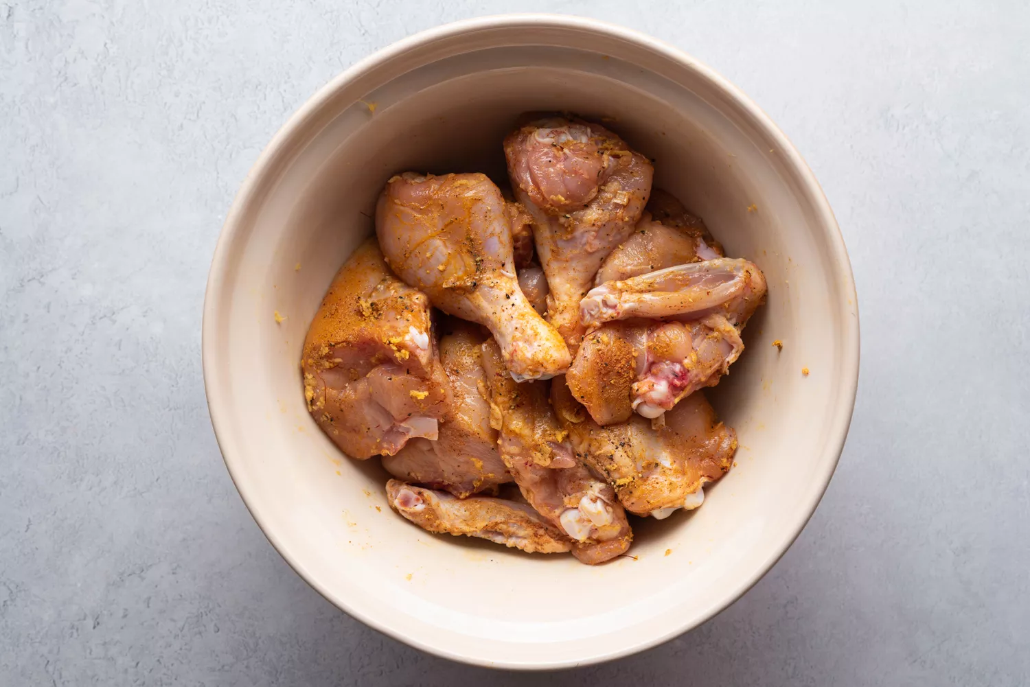 peças de frango misturadas com especiarias em uma tigela