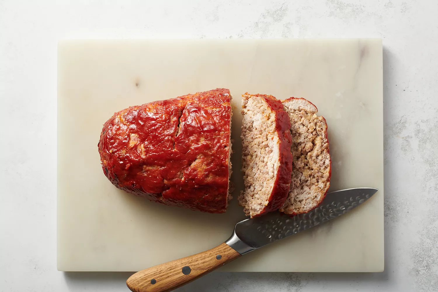 pão de carne de peru fatiado em uma tábua de cortar de mármore