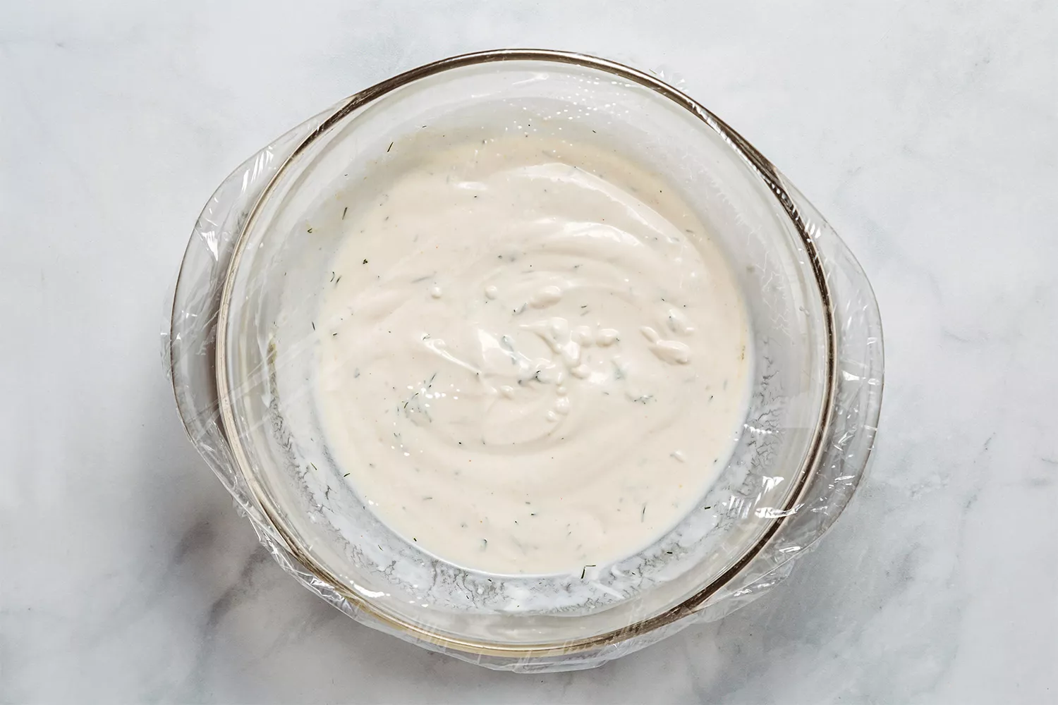 Molho Buttermilk-Ranch em uma tigela, coberto com filme plástico